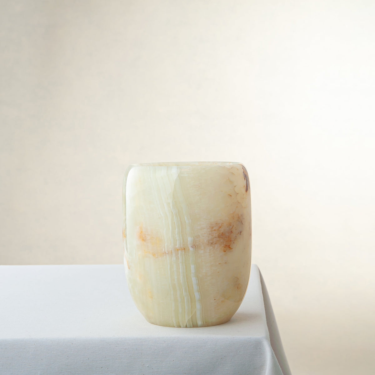 Unique handcrafted white onyx vase with warm amber veining and polished finish
