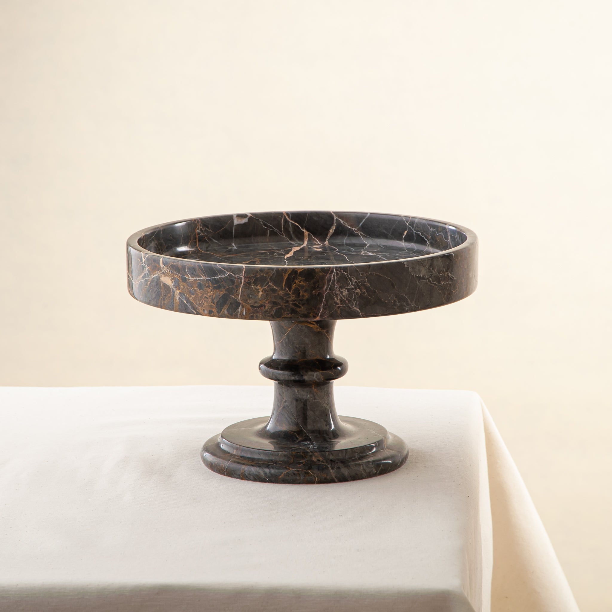 Handcrafted marble bowl with dark tones and warm veining also usable as elegant cake stand
