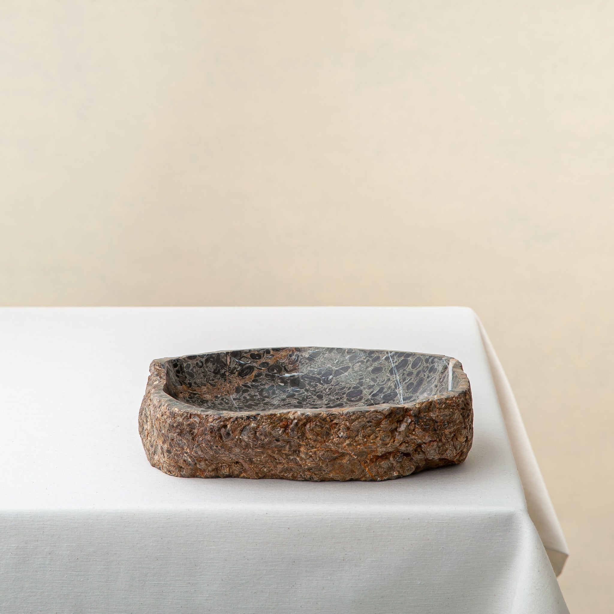 Unique marble bowl with raw textured exterior and polished fossil patterned interior
