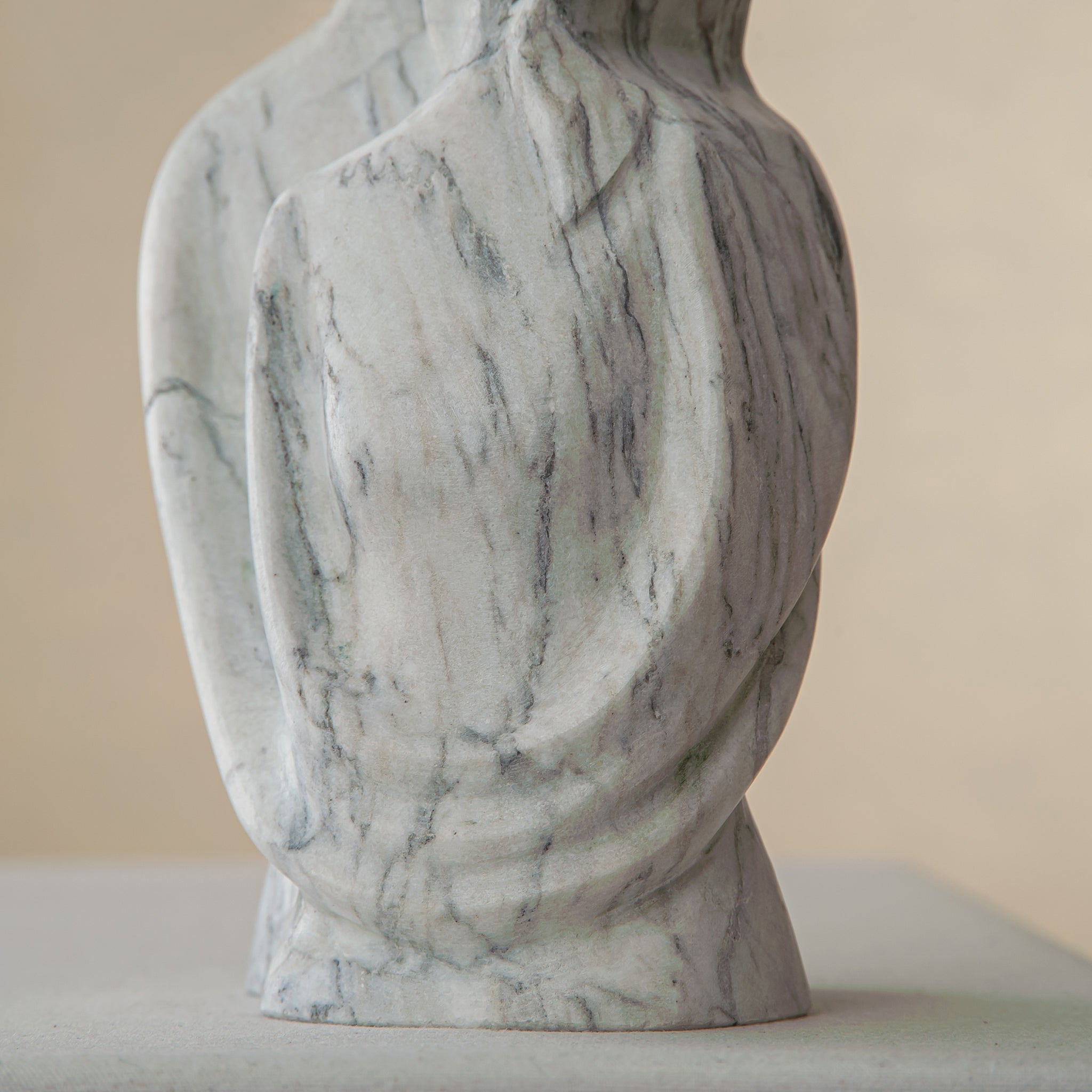 Handcrafted marble sculpture with embracing abstract figures and light black veining
