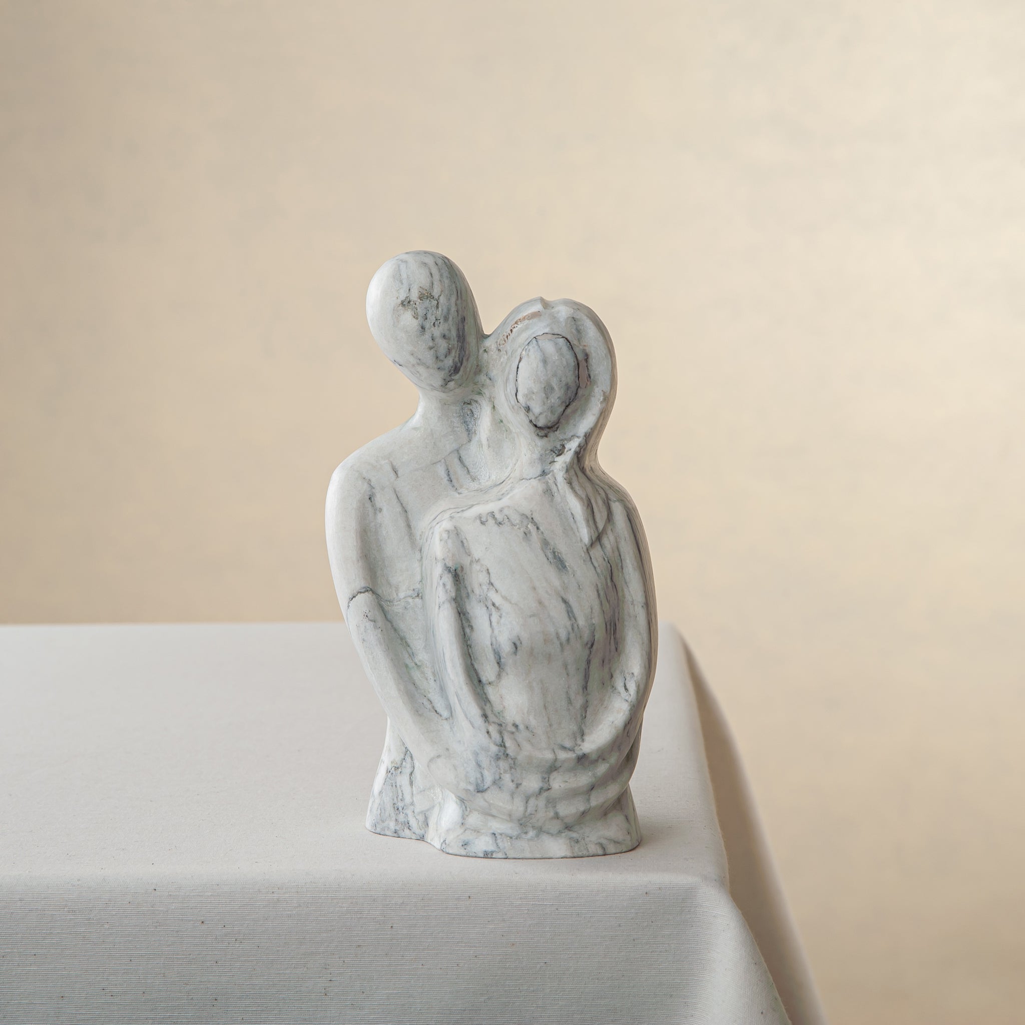 Handcrafted marble sculpture with embracing abstract figures and light black veining
