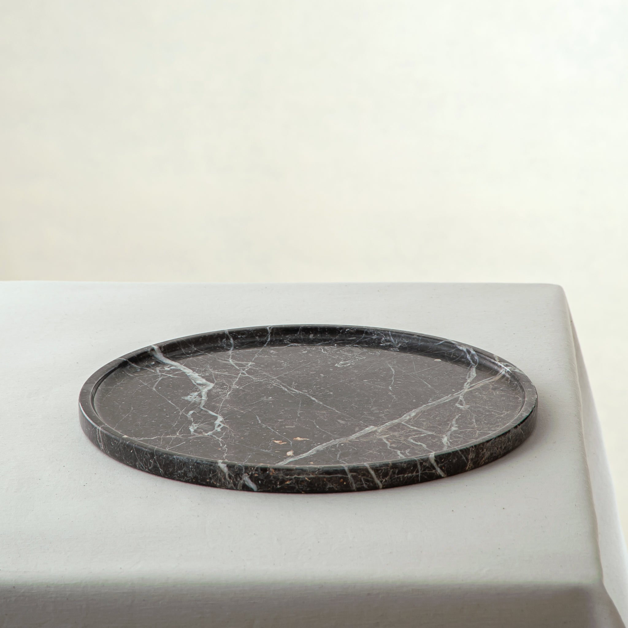 handcrafted marble tray in dark charcoal with white veining and round minimalist design
