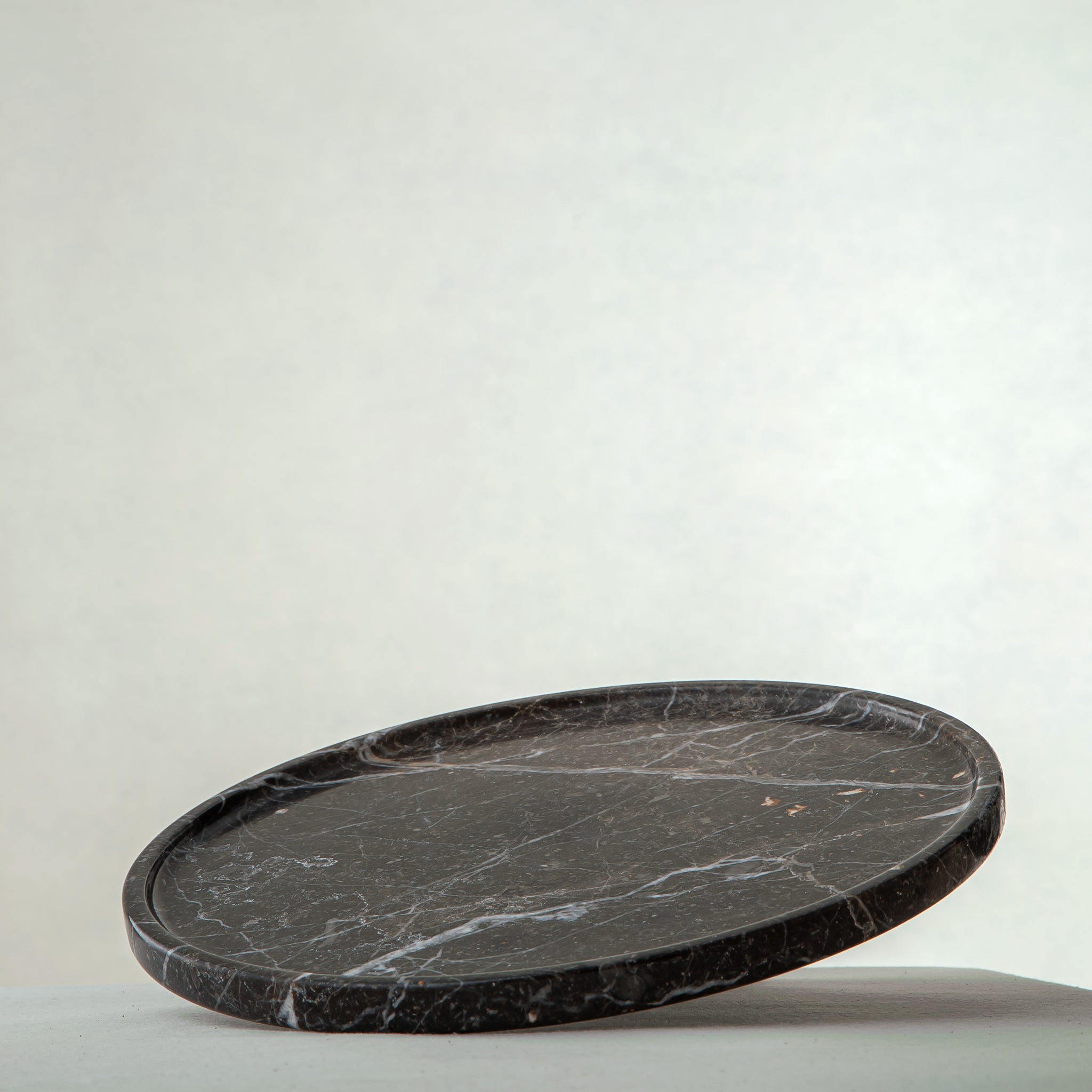 handcrafted marble tray in dark charcoal with white veining and round minimalist design
