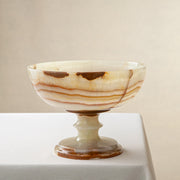 Decorative bowl handcrafted from onyx on a white surface and beige background