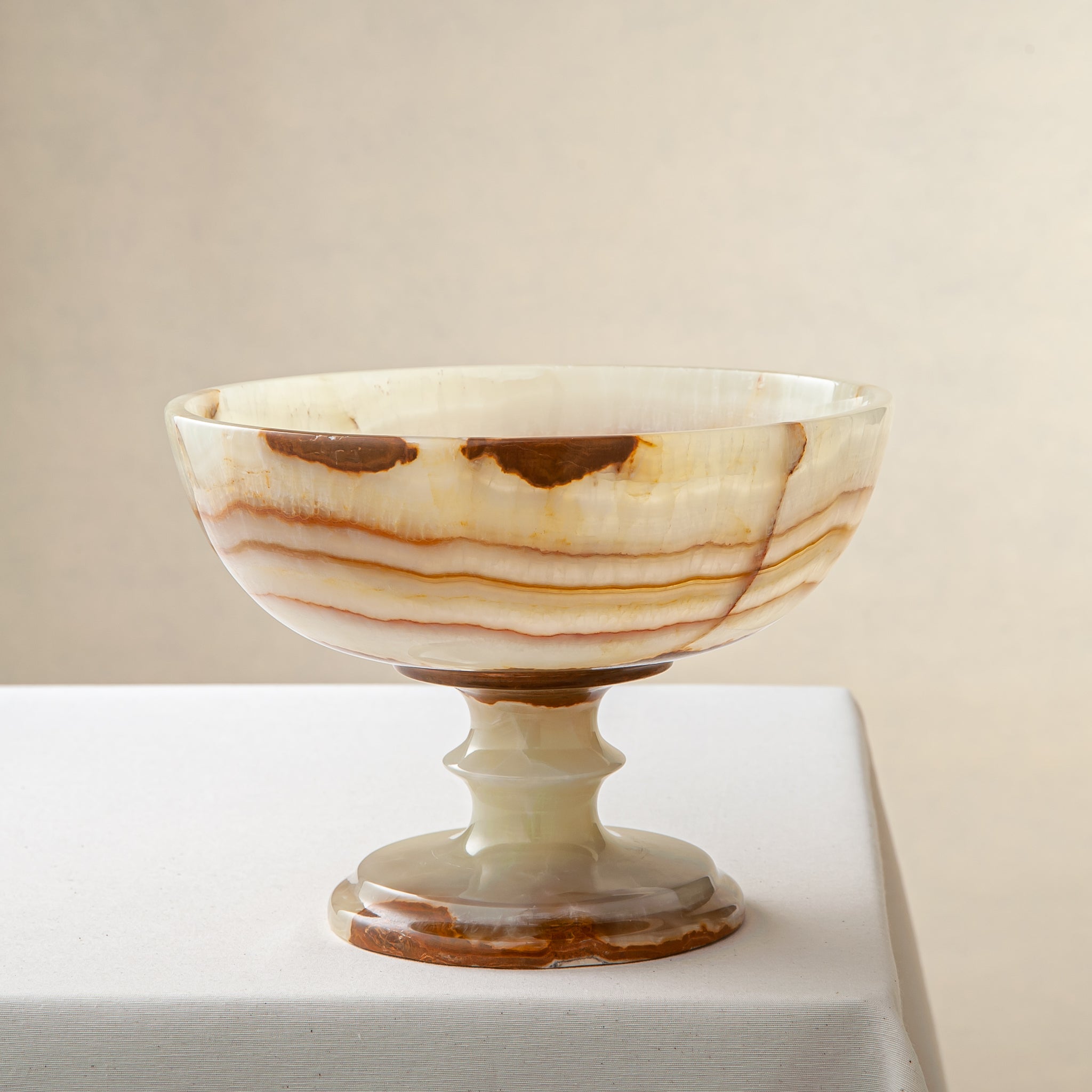 Decorative bowl handcrafted from onyx on a white surface and beige background