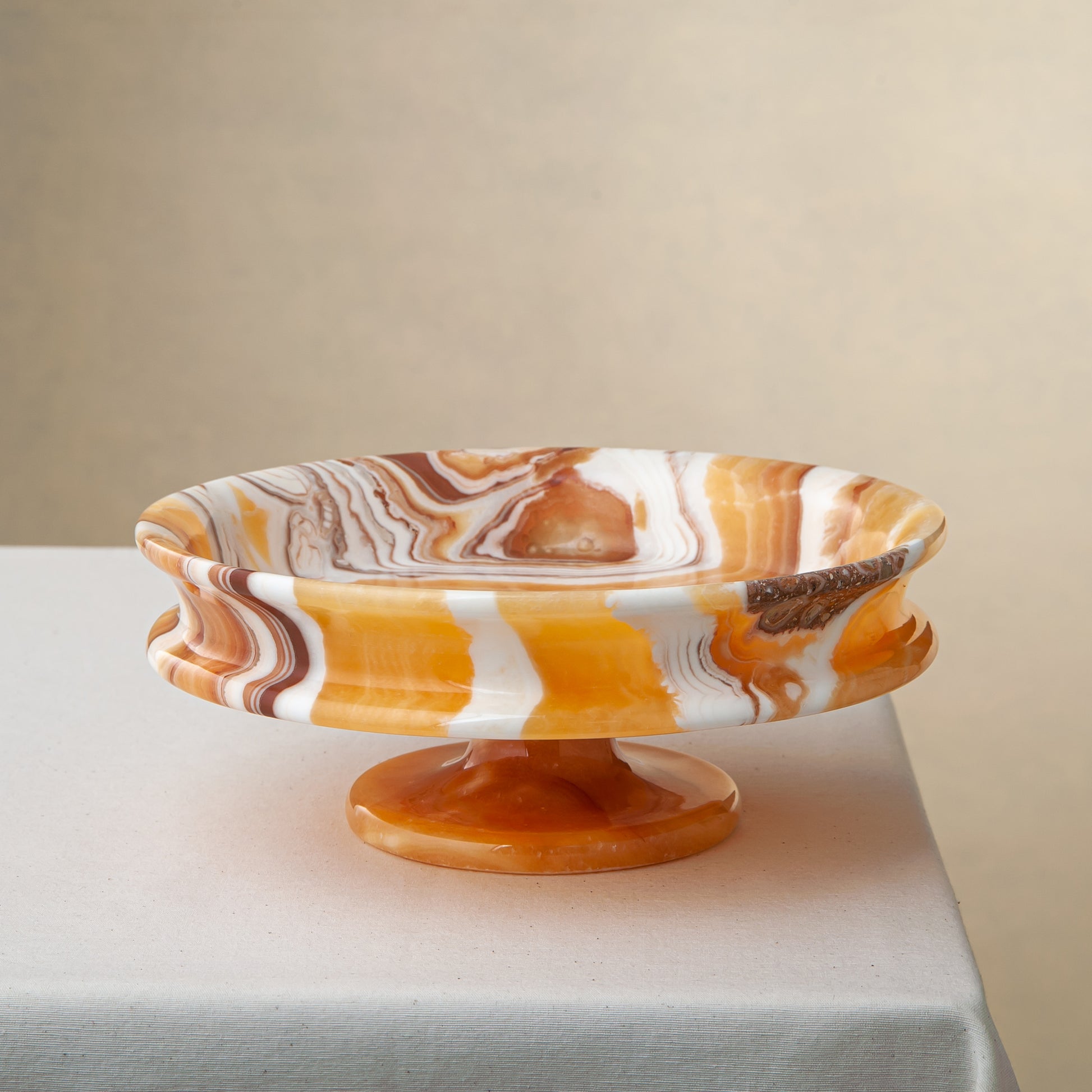 unique natural onyx bowl with warm honey coloration and sculptural pedestal as centerpiece
