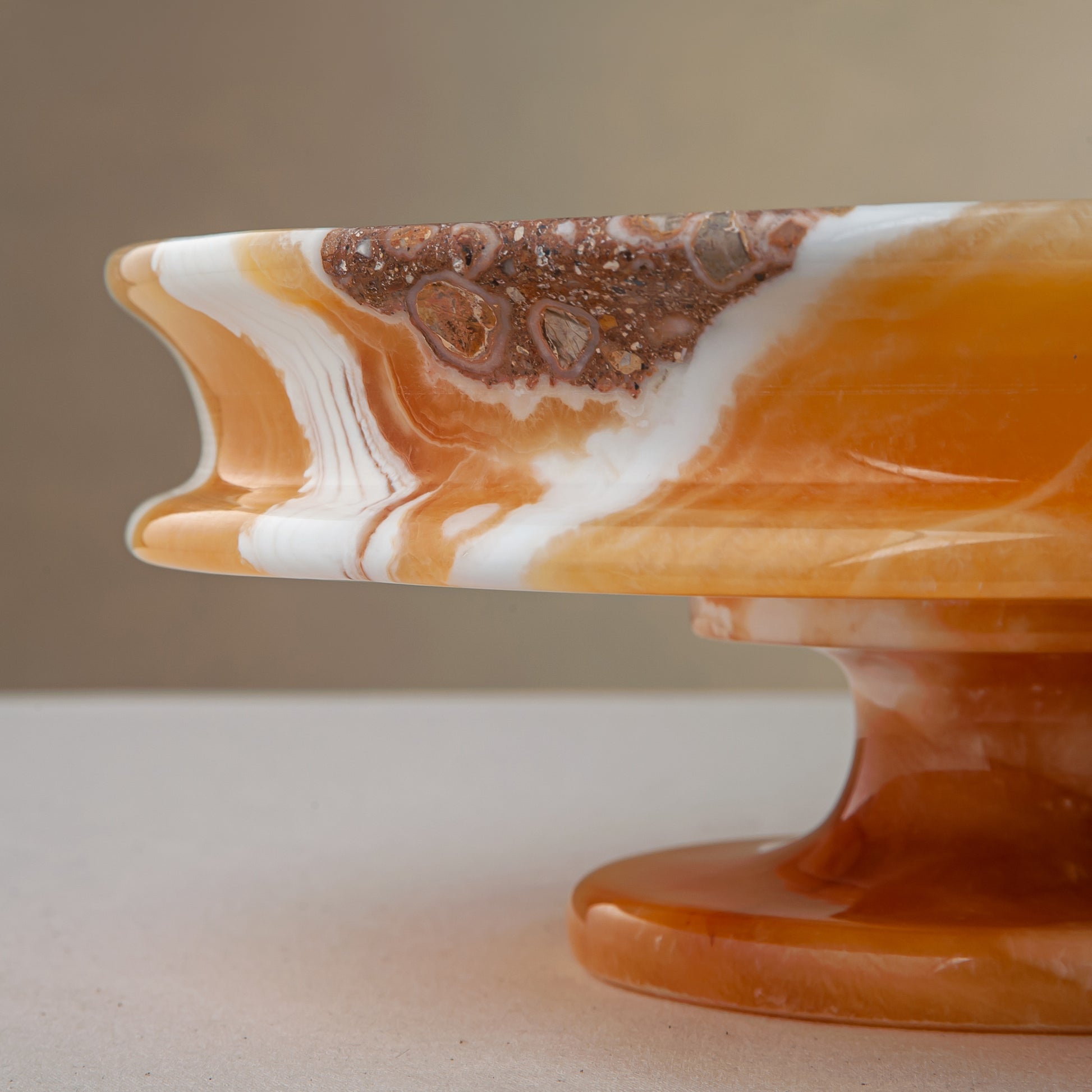 unique natural onyx bowl with warm honey coloration and sculptural pedestal as centerpiece
