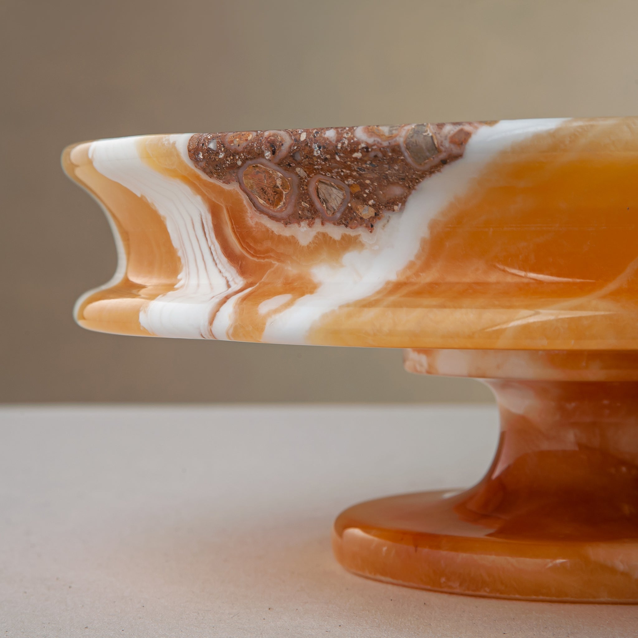 unique natural onyx bowl with warm honey coloration and sculptural pedestal as centerpiece
