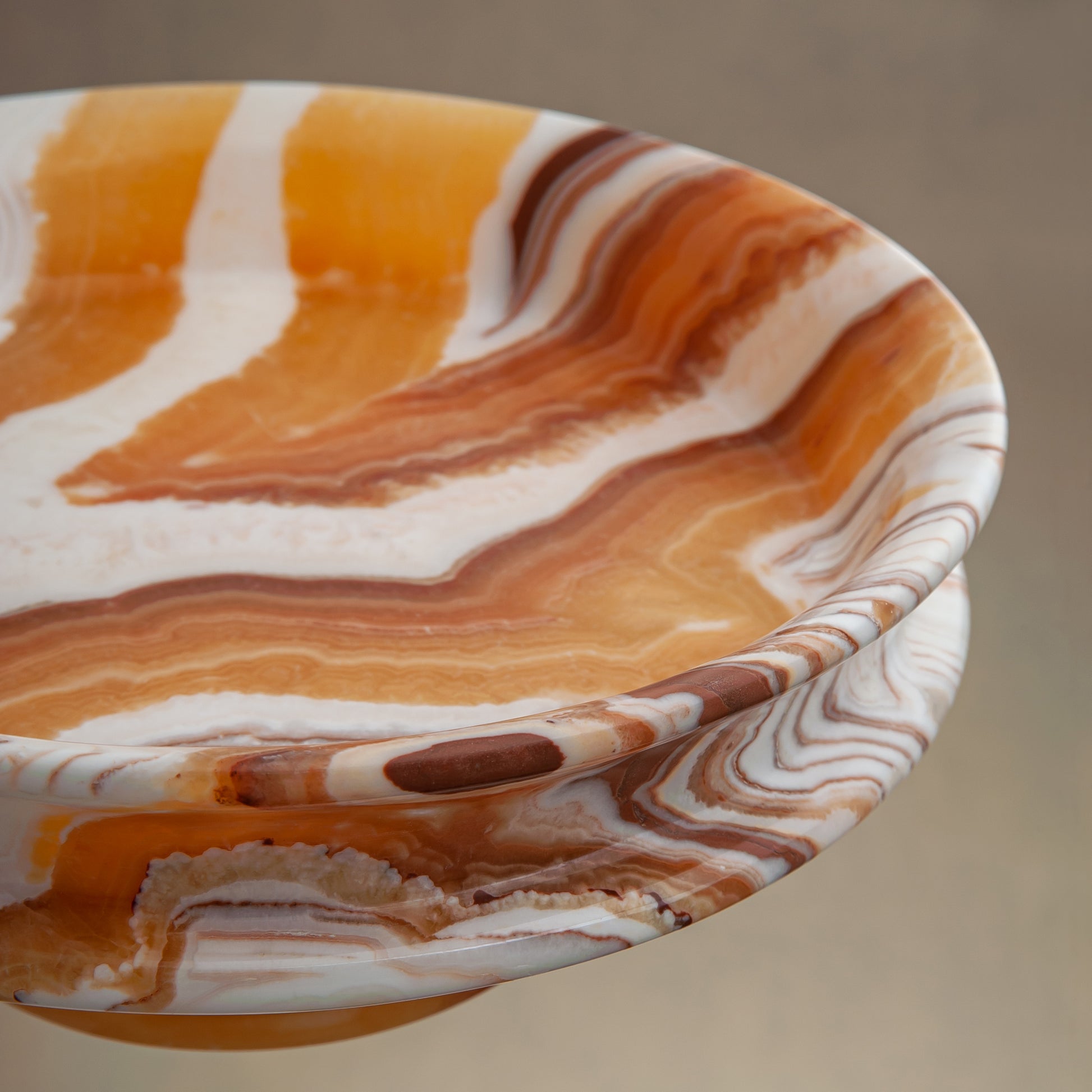 unique natural onyx bowl with warm honey coloration and sculptural pedestal as centerpiece
