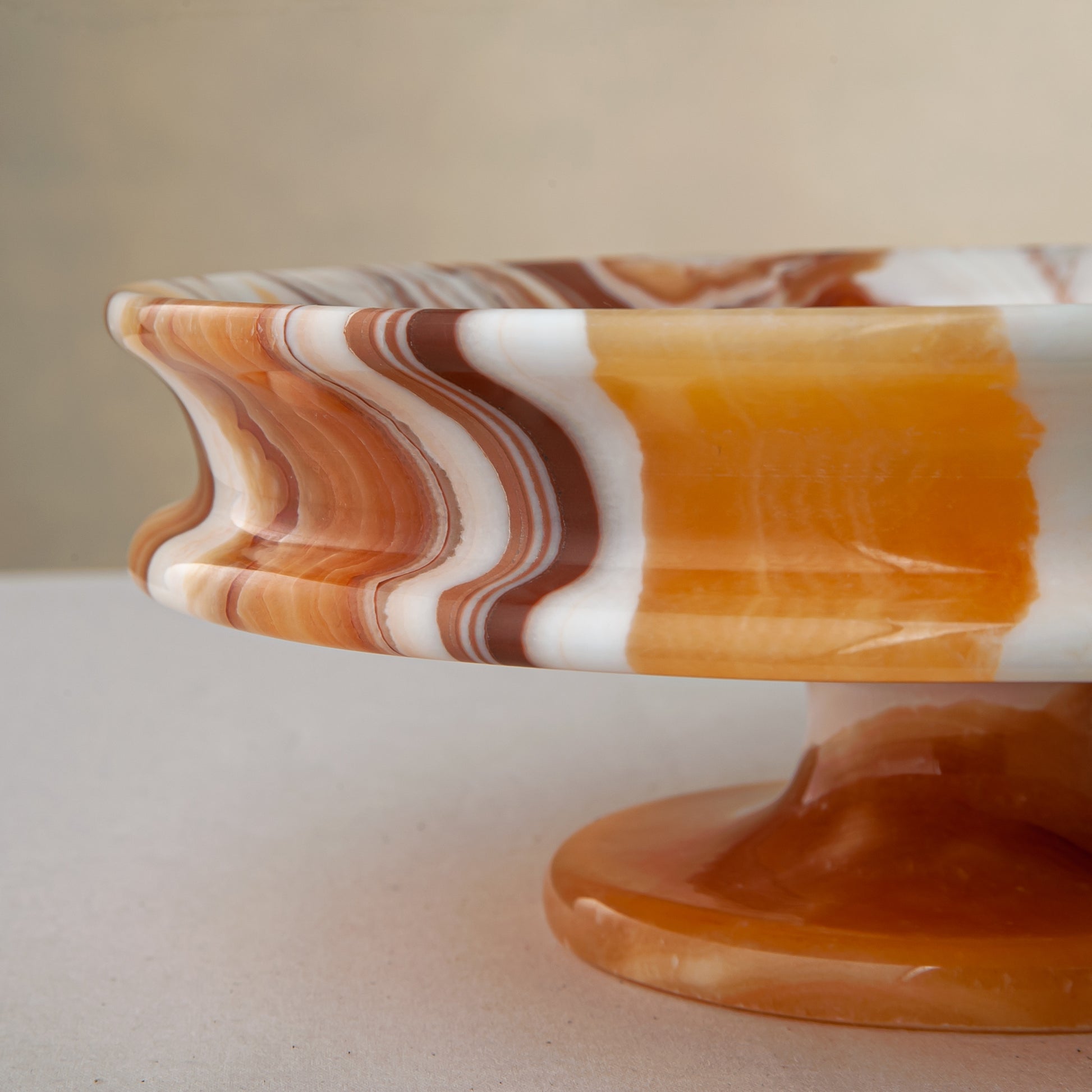 unique natural onyx bowl with warm honey coloration and sculptural pedestal as centerpiece
