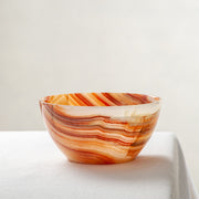 Unique natural onyx bowl in warm orange hues with translucent veining and smooth curved form

