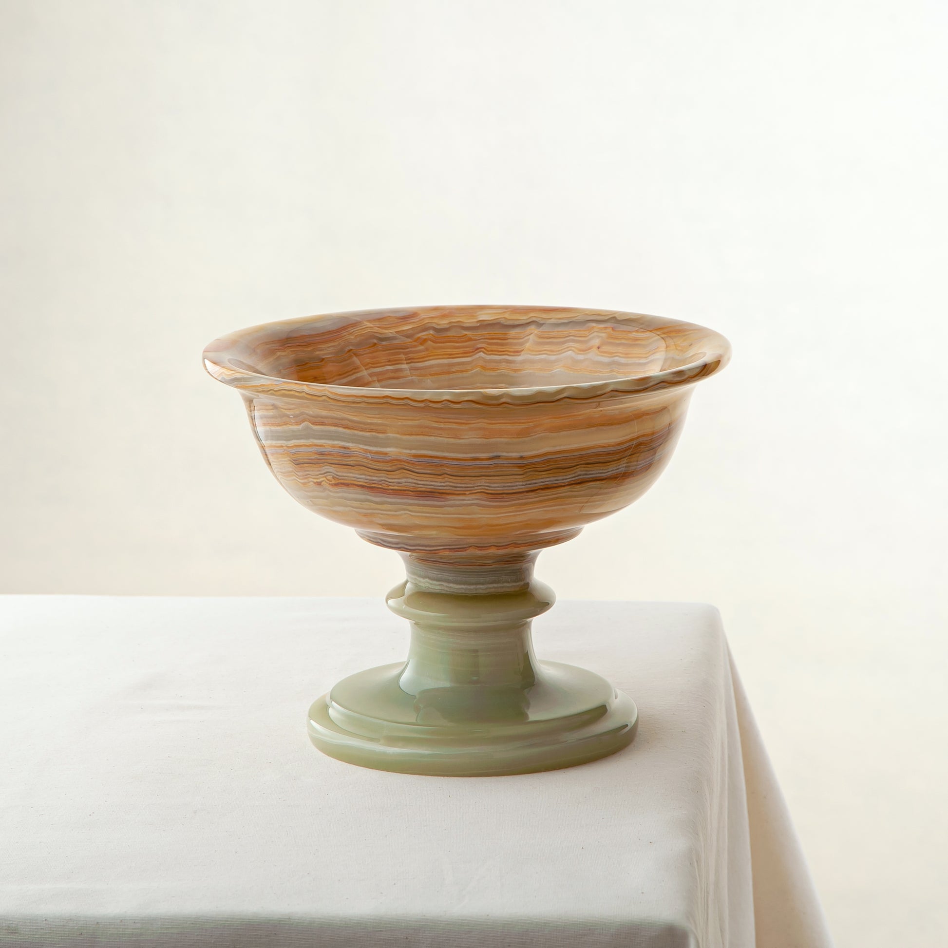 Handcrafted onyx bowl with pedestal base in warm amber veining as sculptural centerpiece

