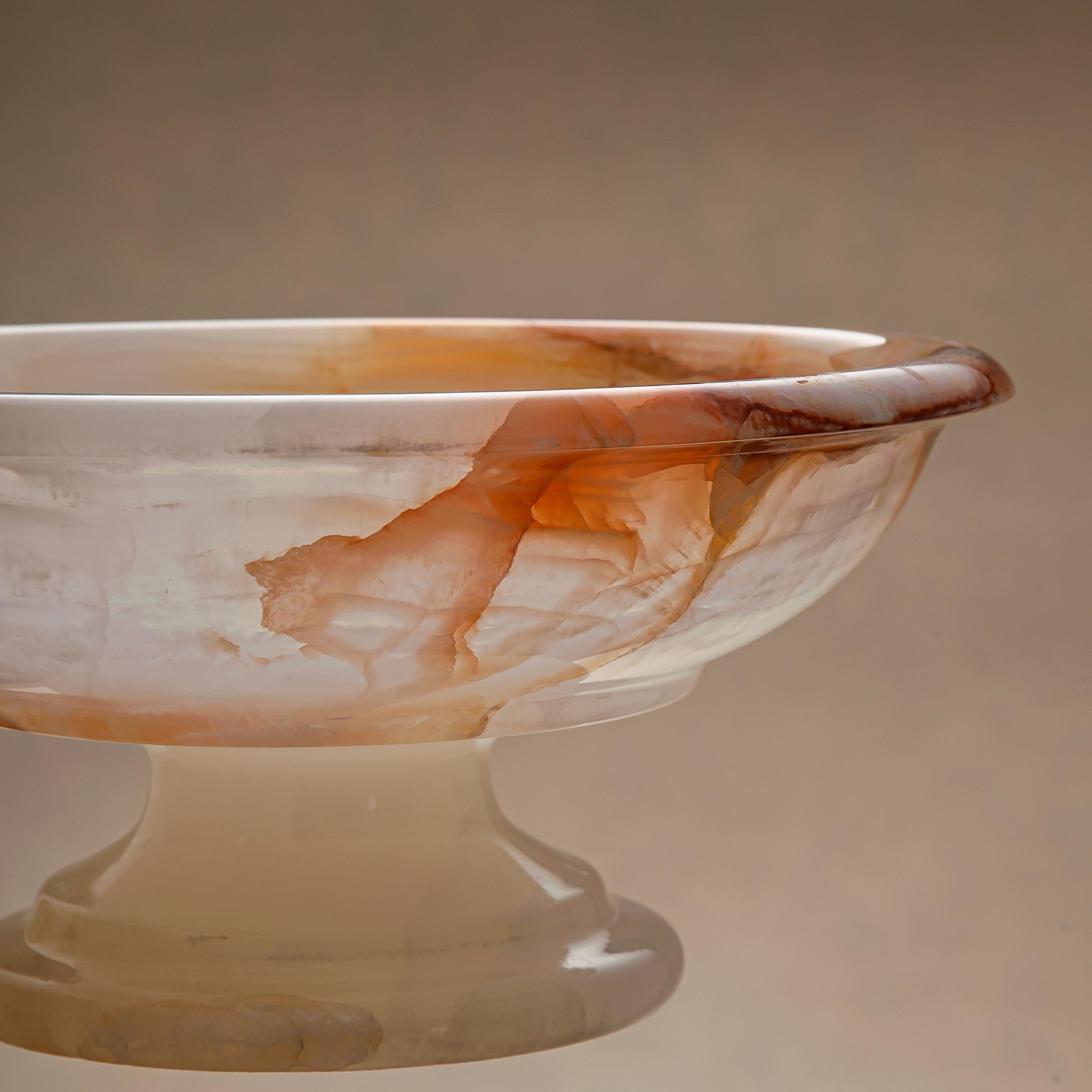 handcrafted onyx bowl with amber veining and translucent ivory stone on pedestal for luxury decor
