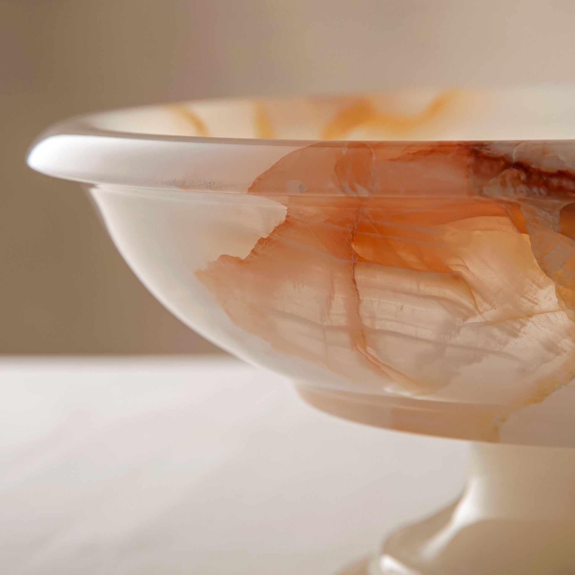 handcrafted onyx bowl with amber veining and translucent ivory stone on pedestal for luxury decor
