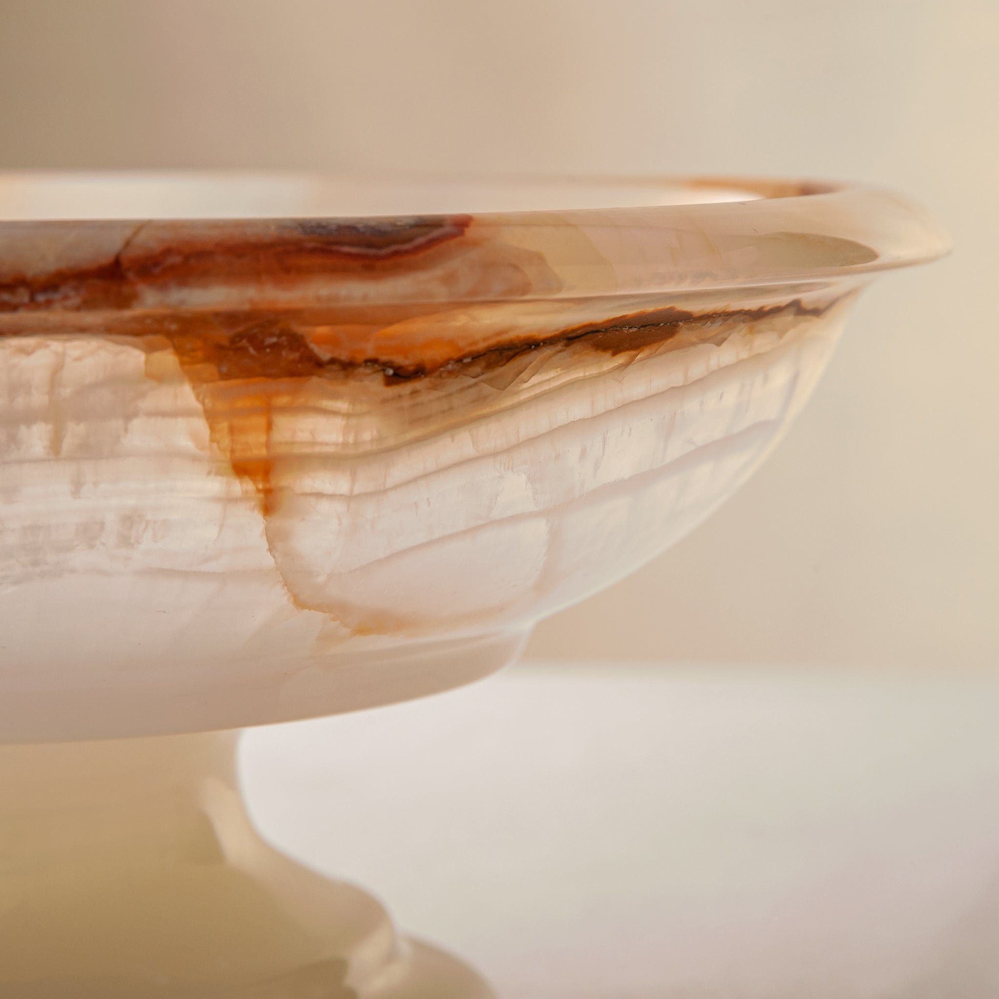 handcrafted onyx bowl with amber veining and translucent ivory stone on pedestal for luxury decor
