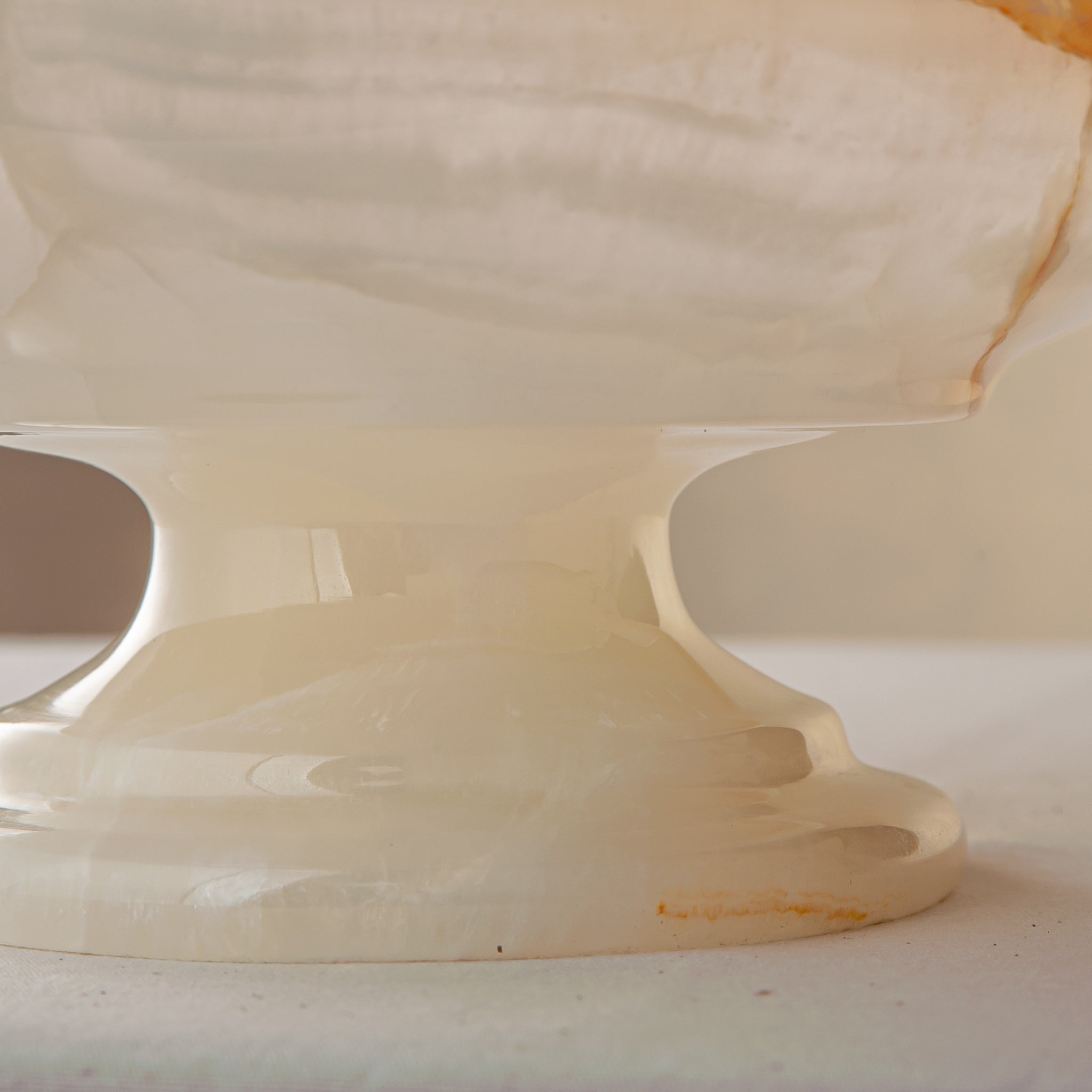handcrafted onyx bowl with amber veining and translucent ivory stone on pedestal for luxury decor
