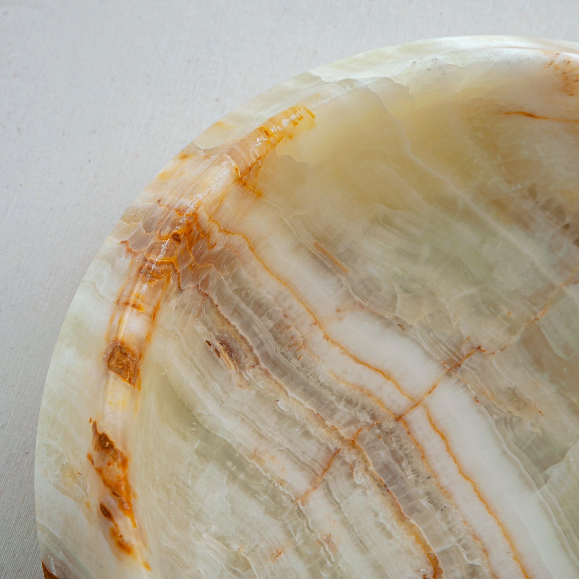 handcrafted onyx bowl with faceted edge and ivory tones with amber veining for luxury decor
