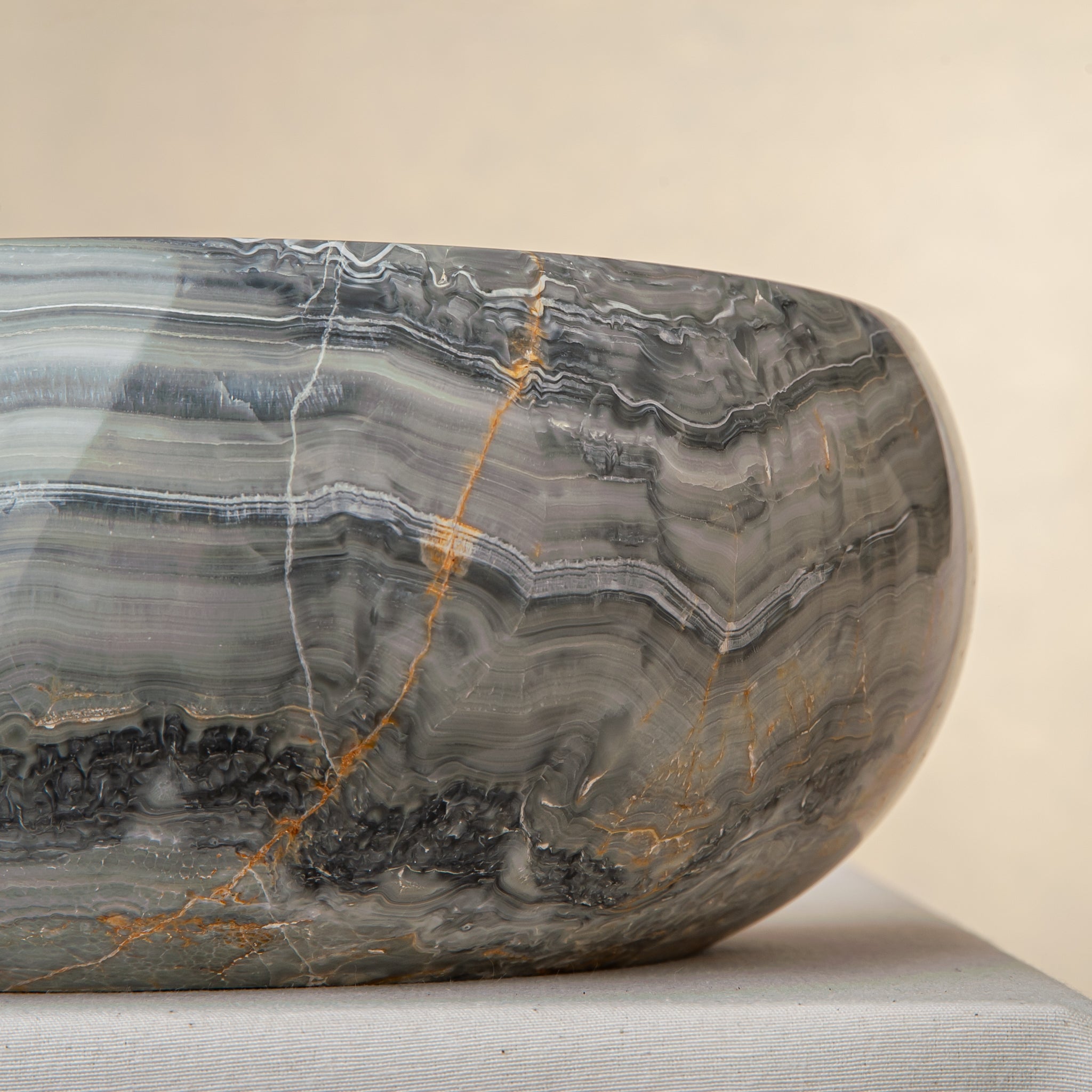 Handcrafted onyx bowl with grey blue banding and amber veining for luxury table decor
