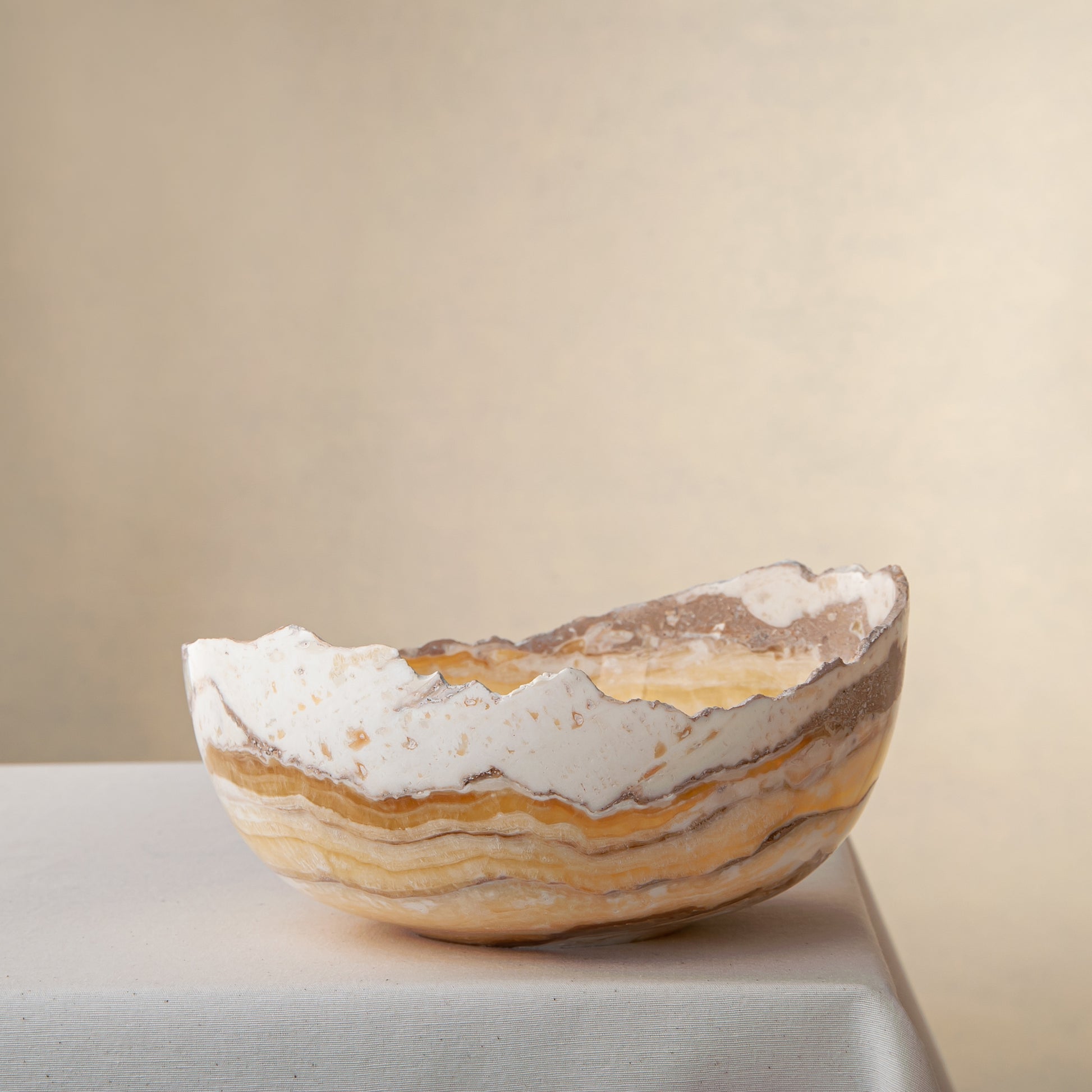 artisanal onyx bowl with translucent amber tones and irregular rim for coffee table styling
