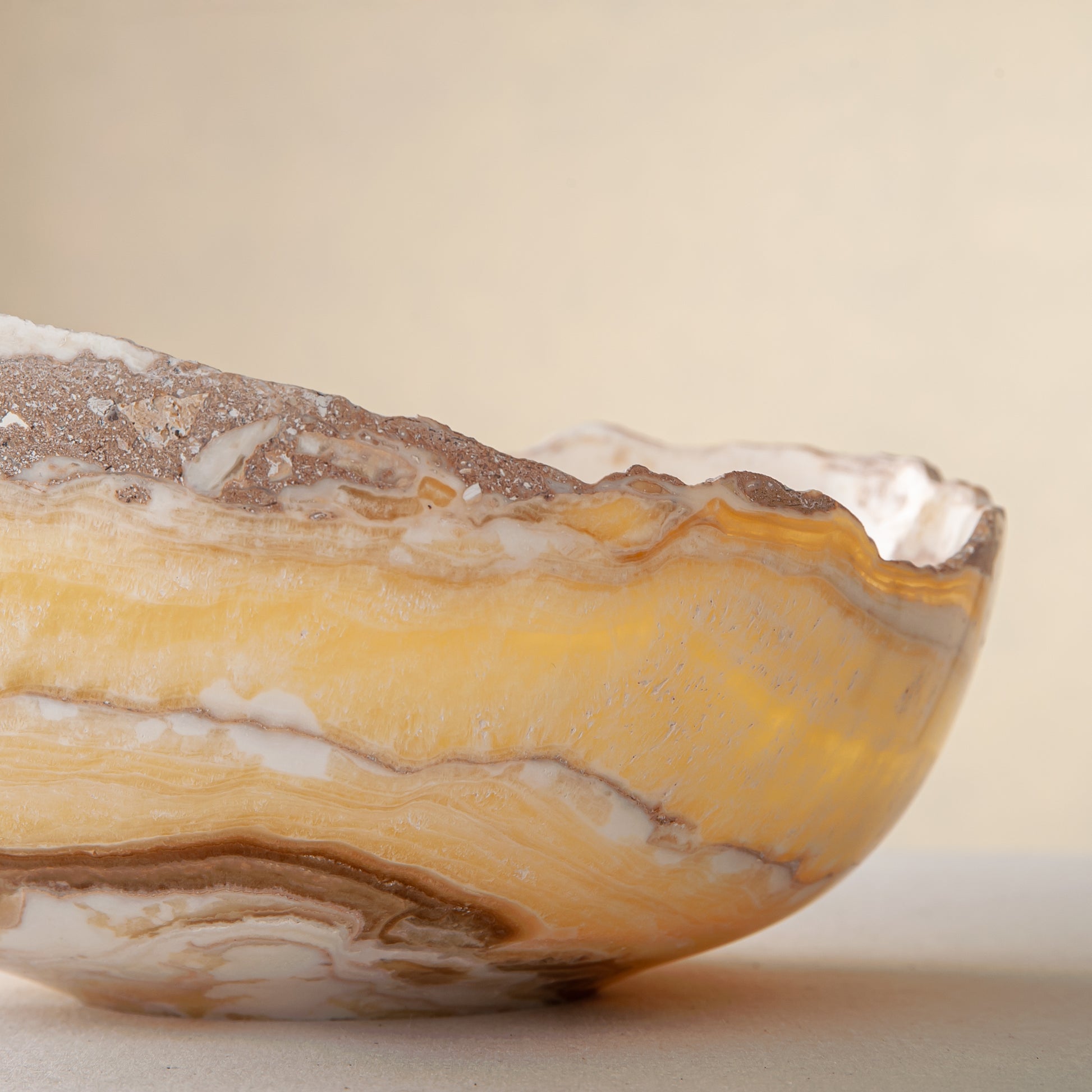 artisanal onyx bowl with translucent amber tones and irregular rim for coffee table styling
