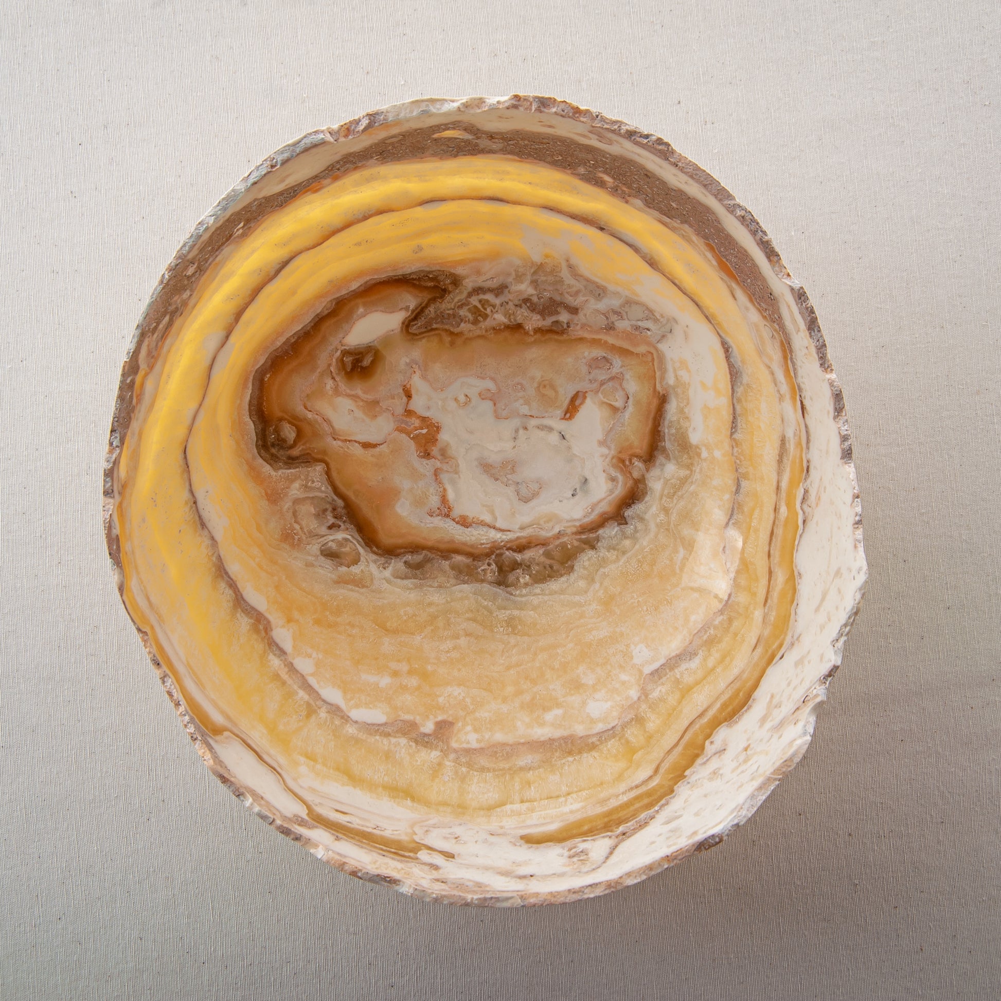 artisanal onyx bowl with translucent amber tones and irregular rim for coffee table styling
