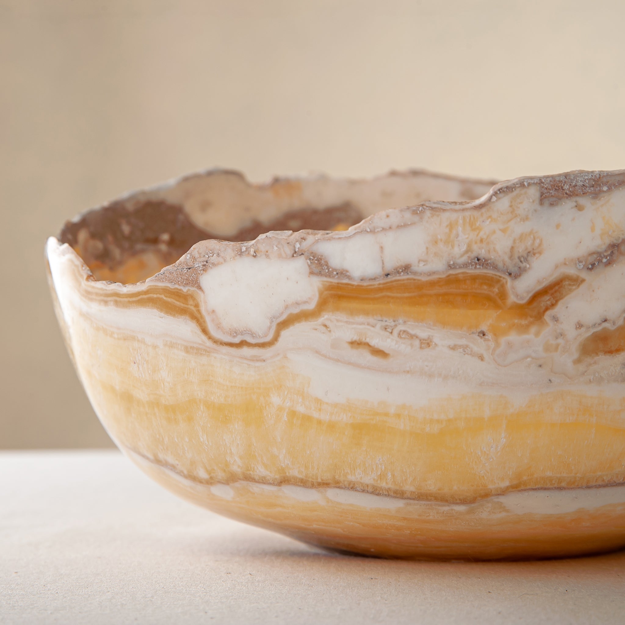 artisanal onyx bowl with translucent amber tones and irregular rim for coffee table styling
