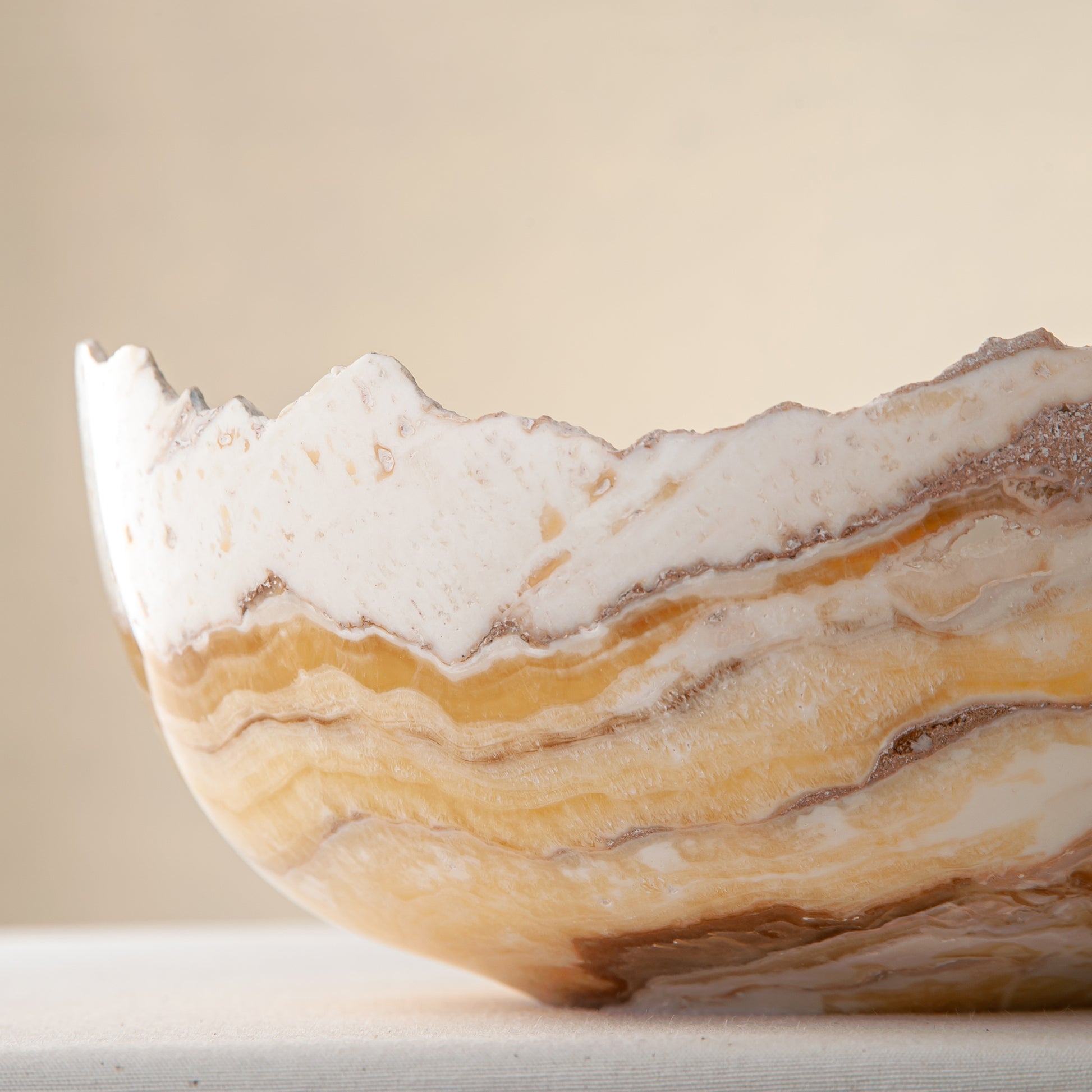 artisanal onyx bowl with translucent amber tones and irregular rim for coffee table styling
