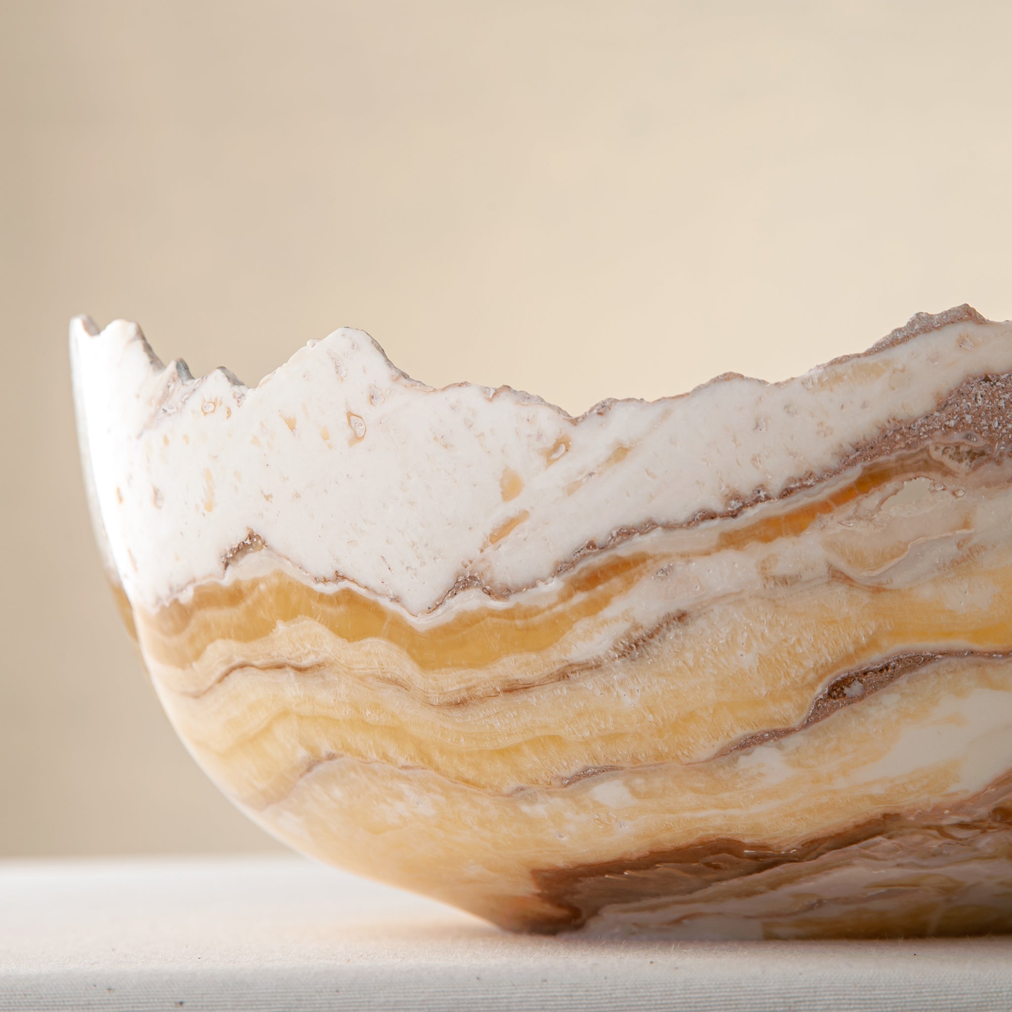artisanal onyx bowl with translucent amber tones and irregular rim for coffee table styling
