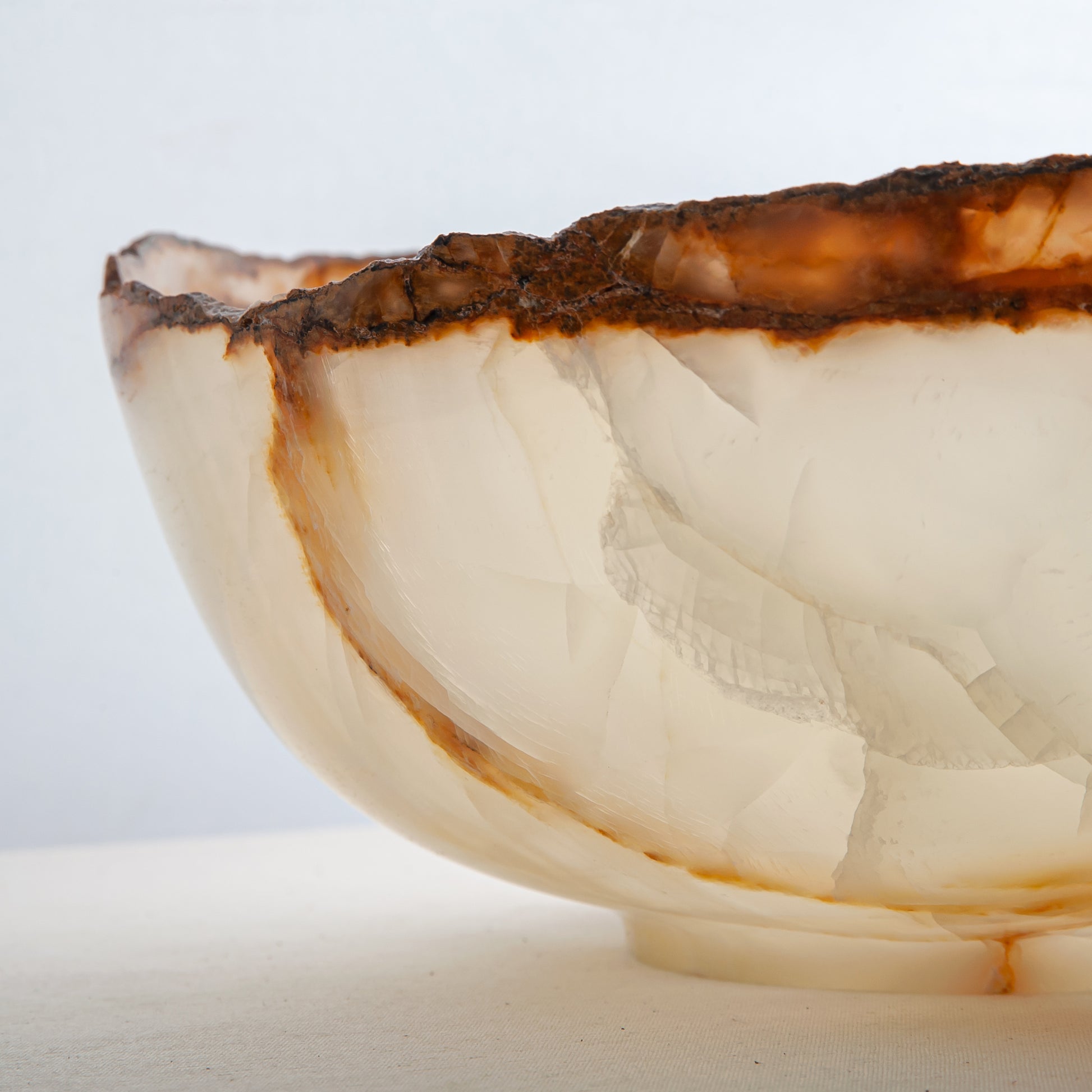 handcrafted onyx bowl with ivory translucency and amber veining with organic edge for luxury decor
