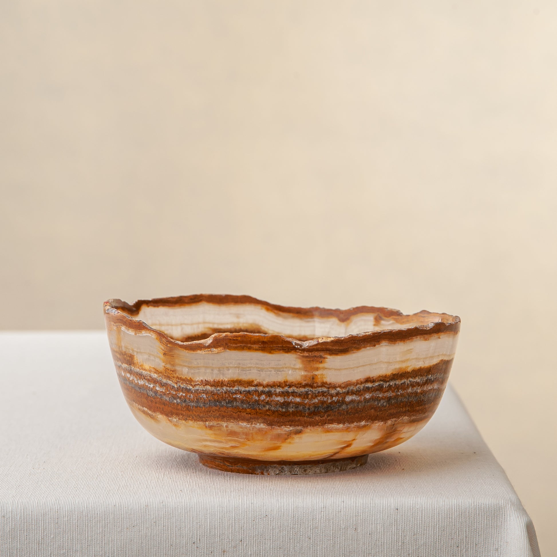 handcrafted onyx bowl with layered amber rust banding and organic edge for luxury decor

