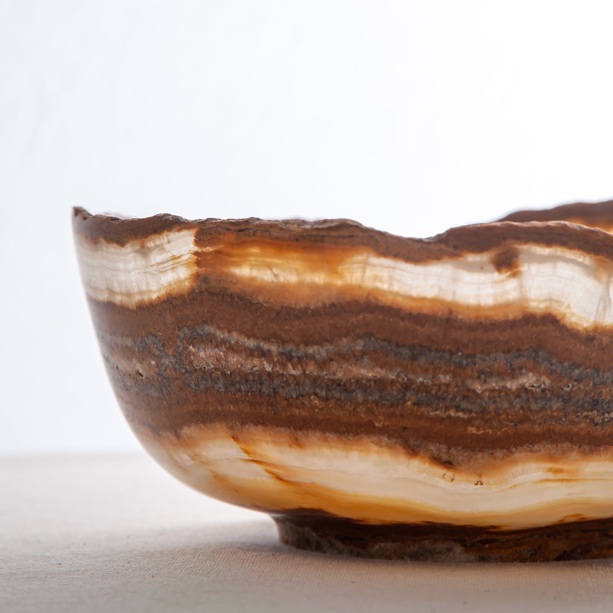 handcrafted onyx bowl with layered amber rust banding and organic edge for luxury decor
