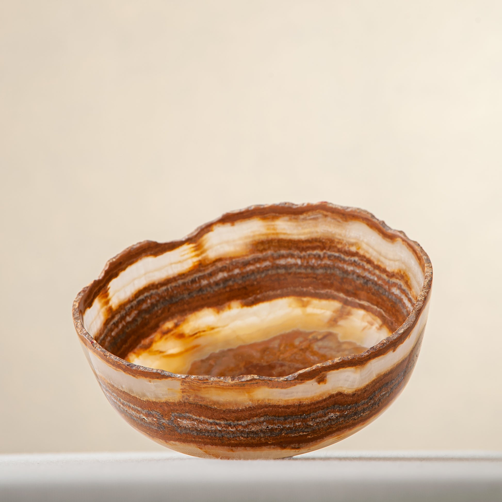 handcrafted onyx bowl with layered amber rust banding and organic edge for luxury decor

