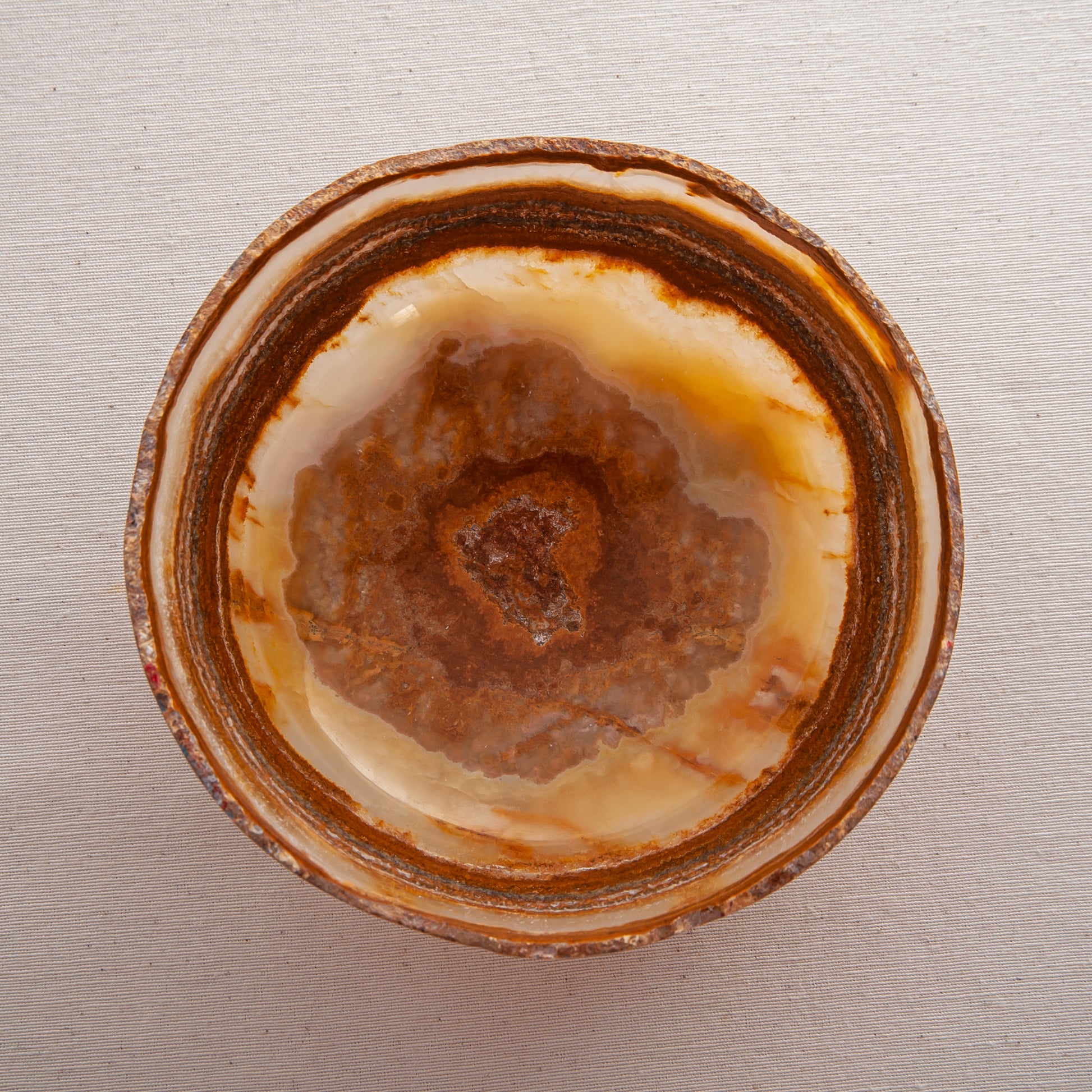 handcrafted onyx bowl with layered amber rust banding and organic edge for luxury decor
