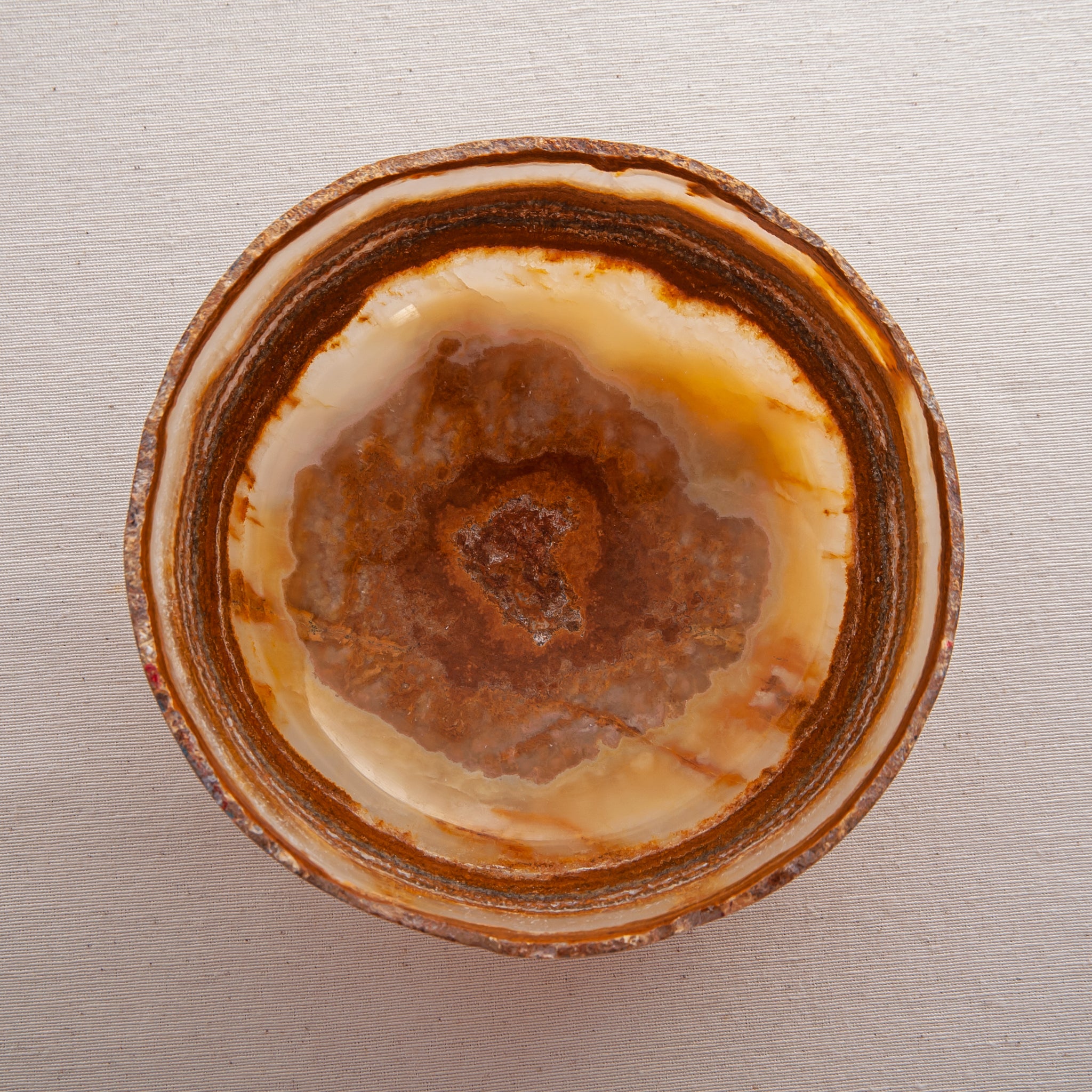 handcrafted onyx bowl with layered amber rust banding and organic edge for luxury decor
