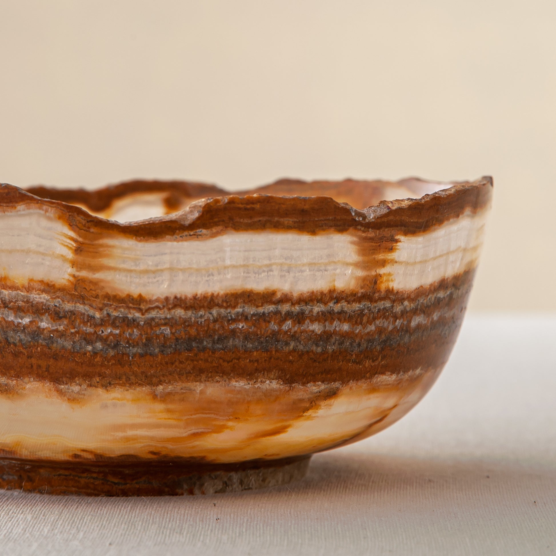 handcrafted onyx bowl with layered amber rust banding and organic edge for luxury decor

