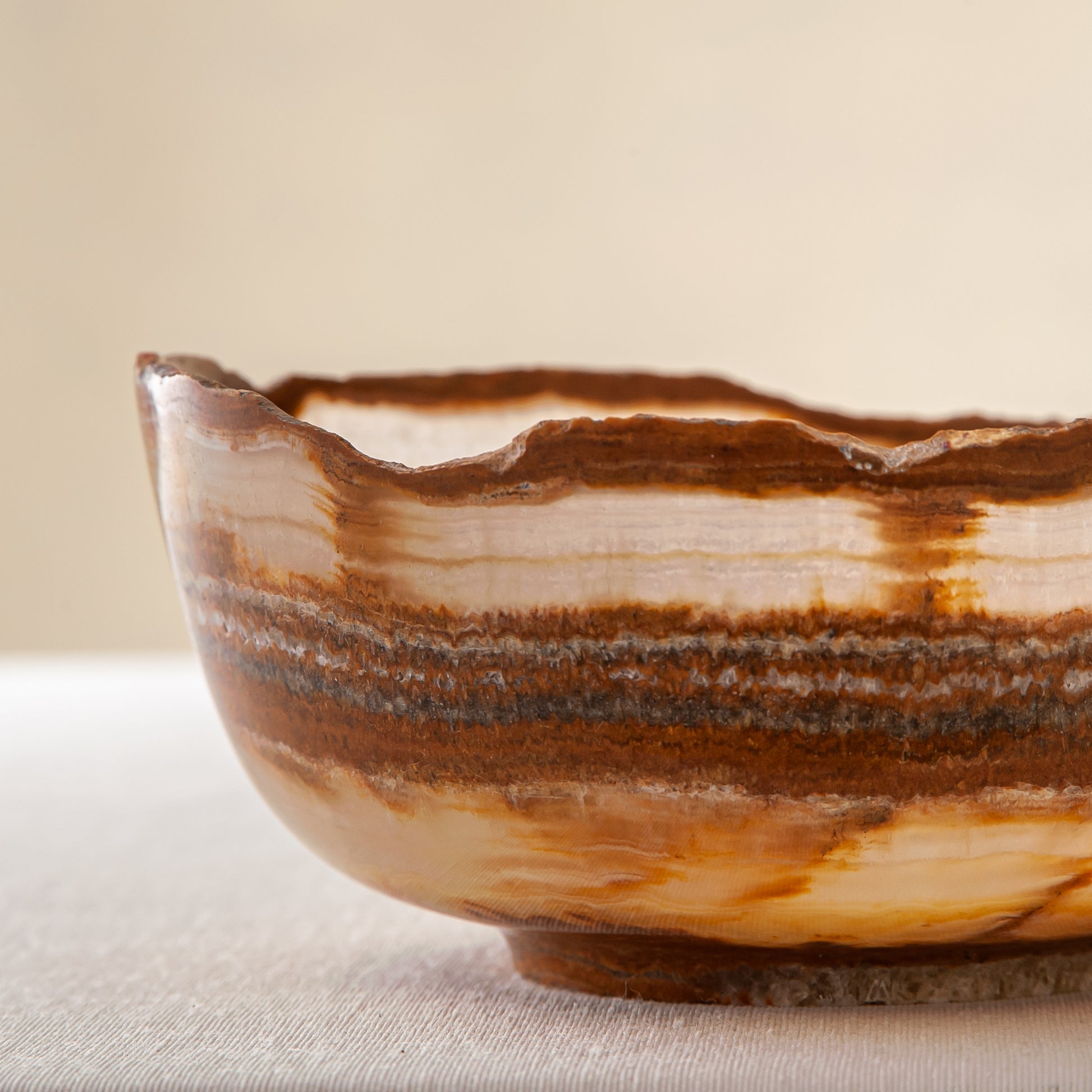 handcrafted onyx bowl with layered amber rust banding and organic edge for luxury decor
