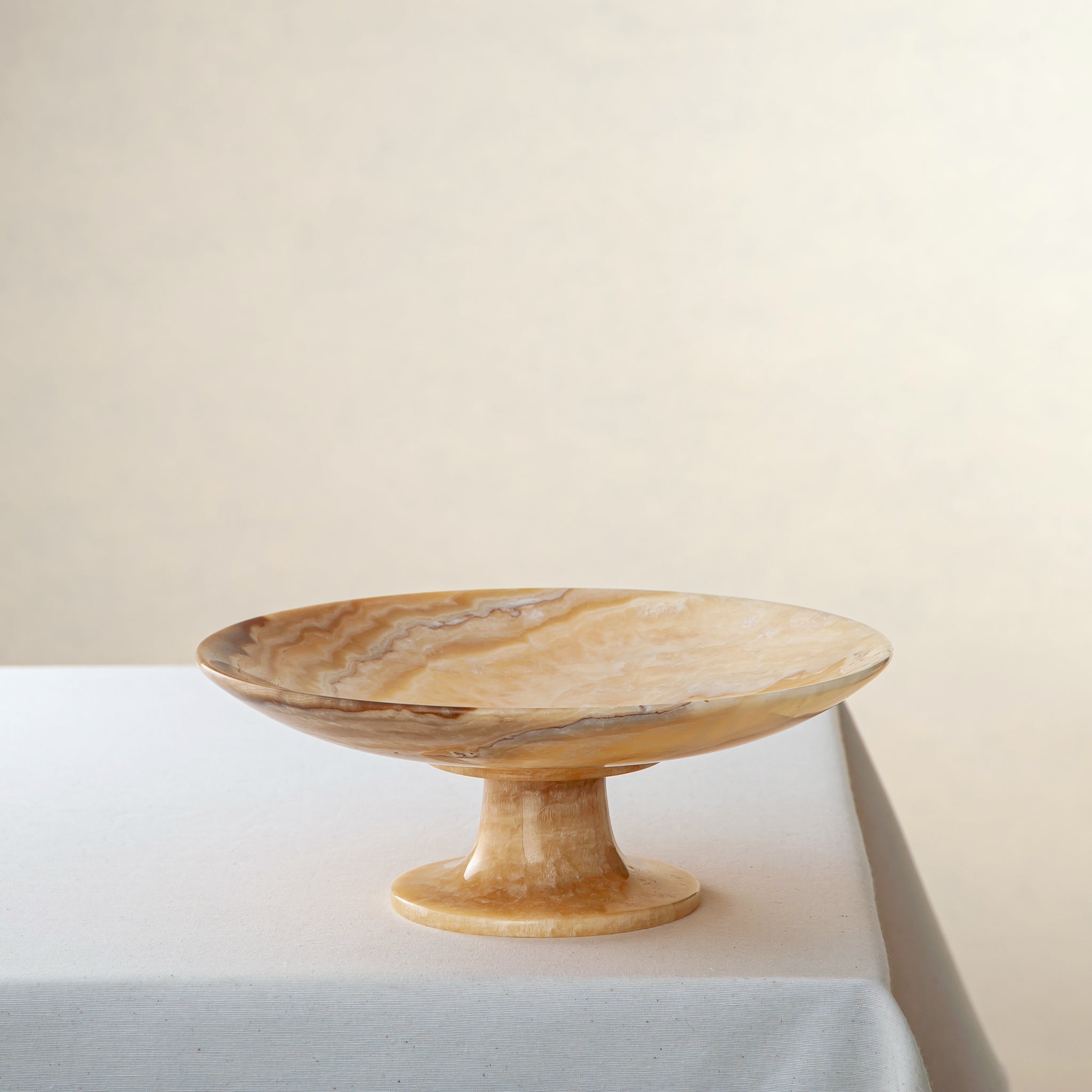 Unique onyx bowl with elevated pedestal base and warm honey veining

