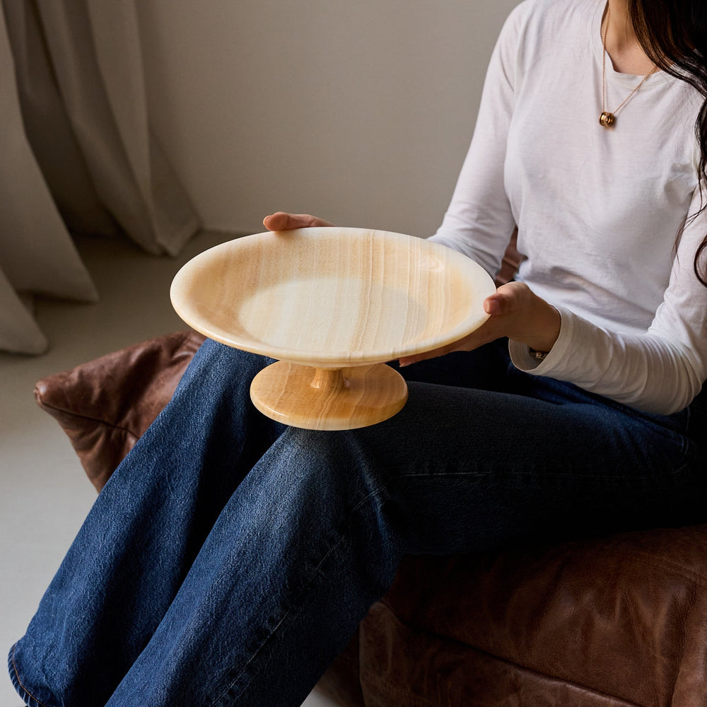 Unique onyx bowl with elevated pedestal base and warm honey veining
