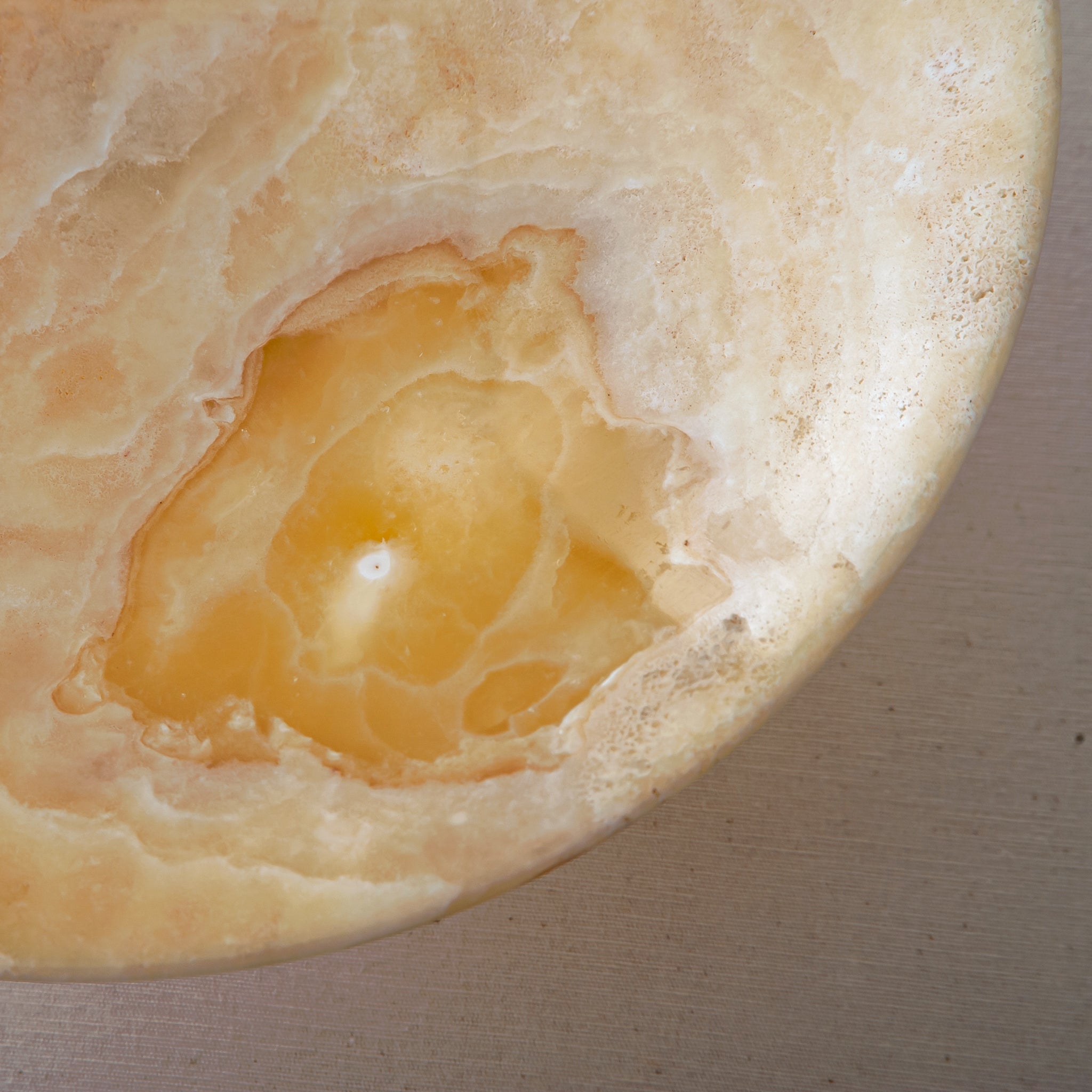 Unique onyx bowl with elevated pedestal base and warm honey veining
