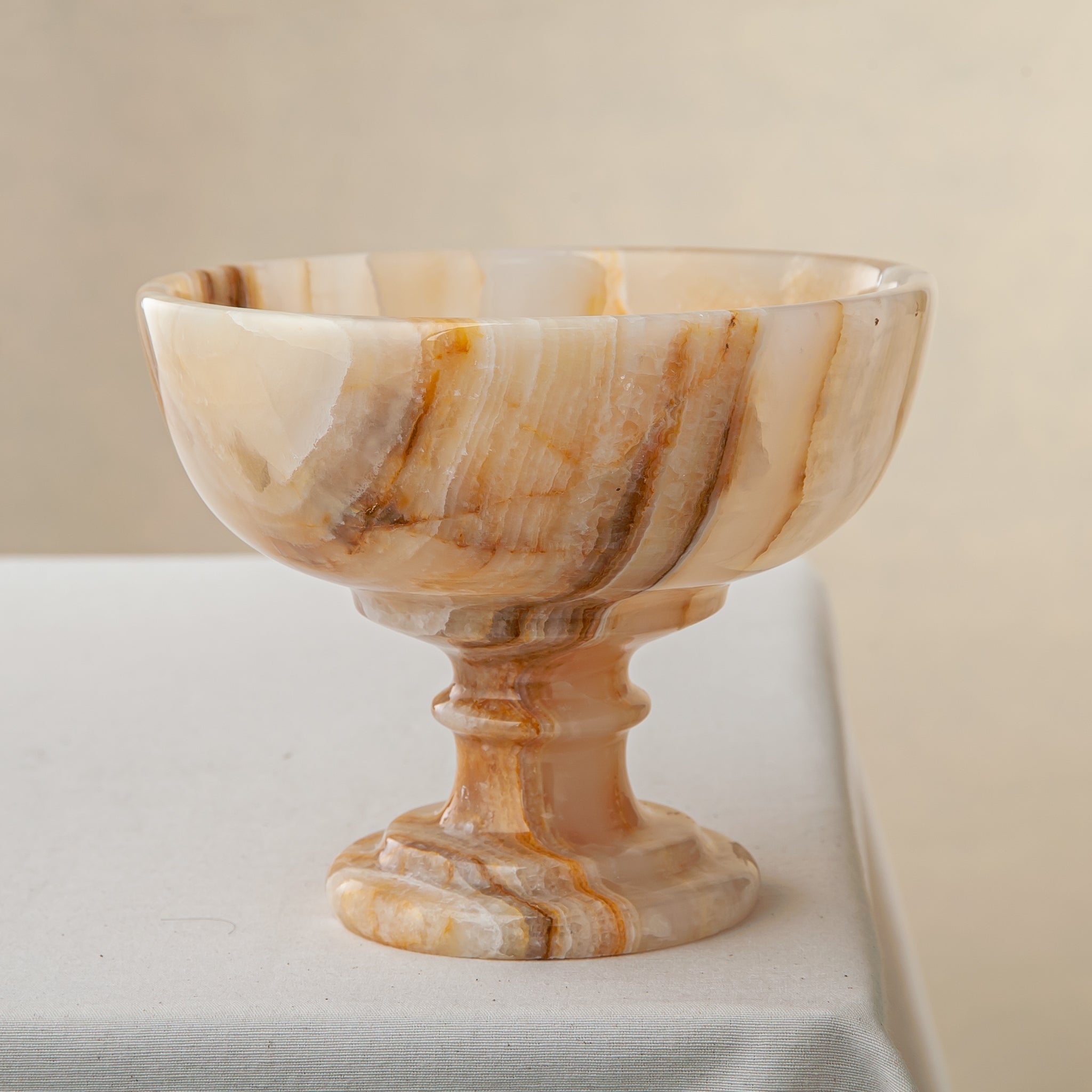 Unique natural onyx bowl with warm honey hues and elevated sculptural form for centerpiece styling
