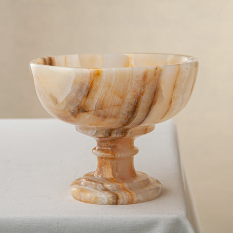 Unique natural onyx bowl with warm honey hues and elevated sculptural form for centerpiece styling
