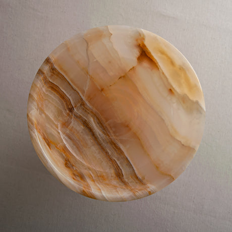 Unique natural onyx bowl with warm honey hues and elevated sculptural form for centerpiece styling
