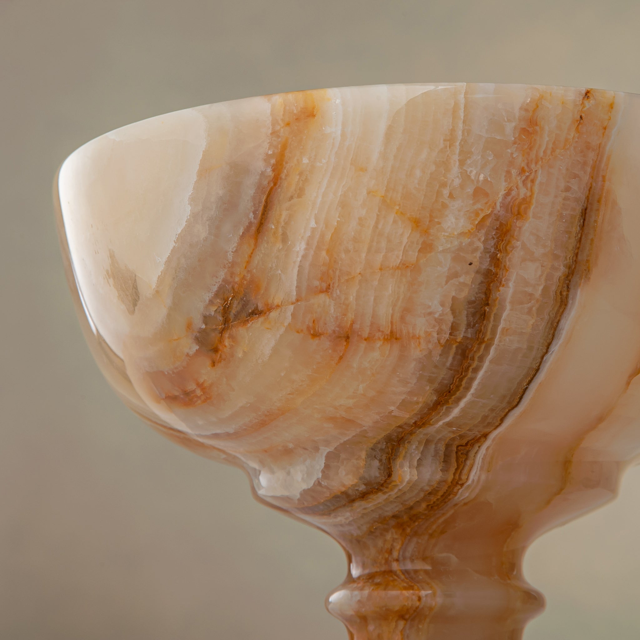 Unique natural onyx bowl with warm honey hues and elevated sculptural form for centerpiece styling

