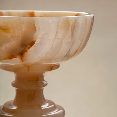 Unique natural onyx bowl with warm honey hues and elevated sculptural form for centerpiece styling
