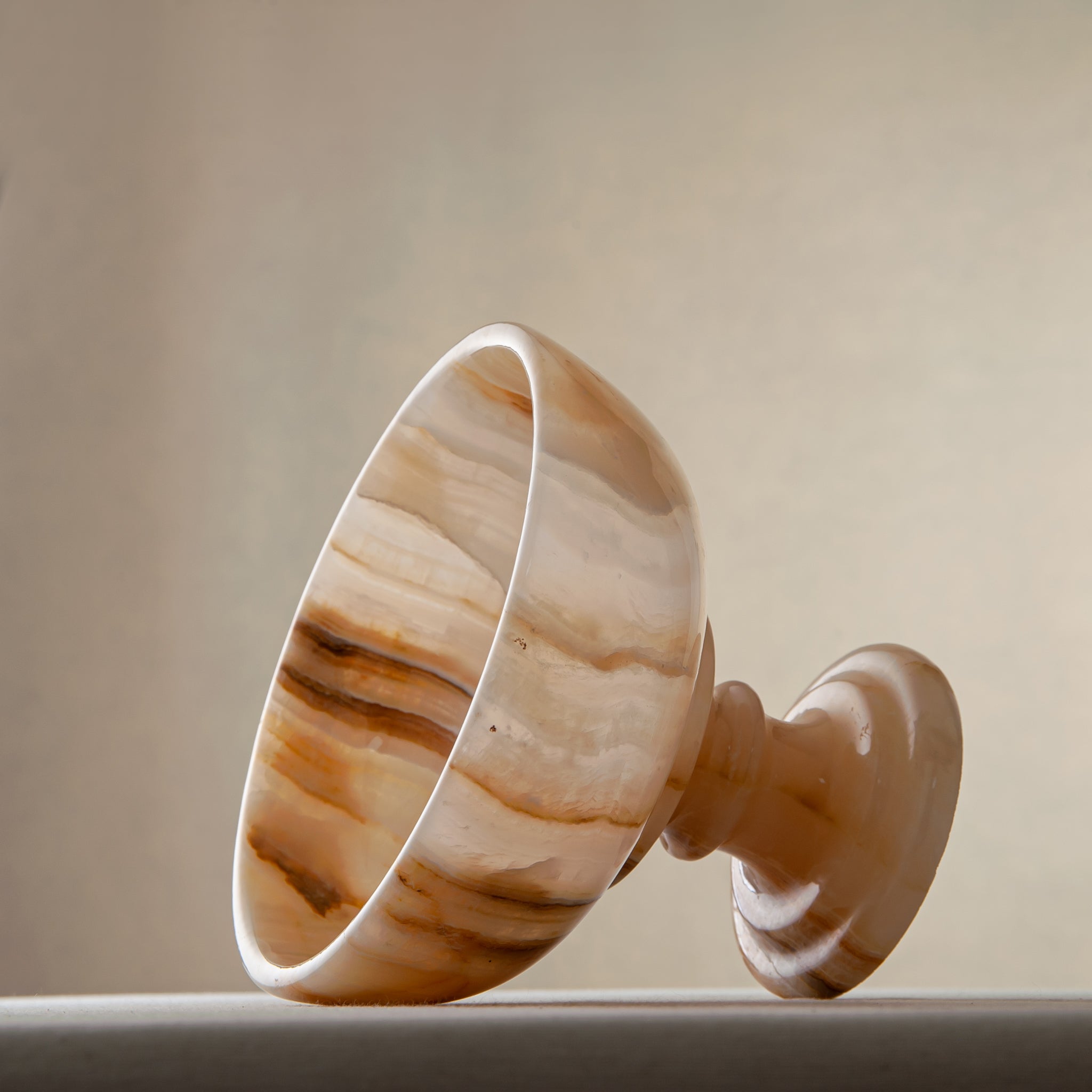 Unique natural onyx bowl with warm honey hues and elevated sculptural form for centerpiece styling
