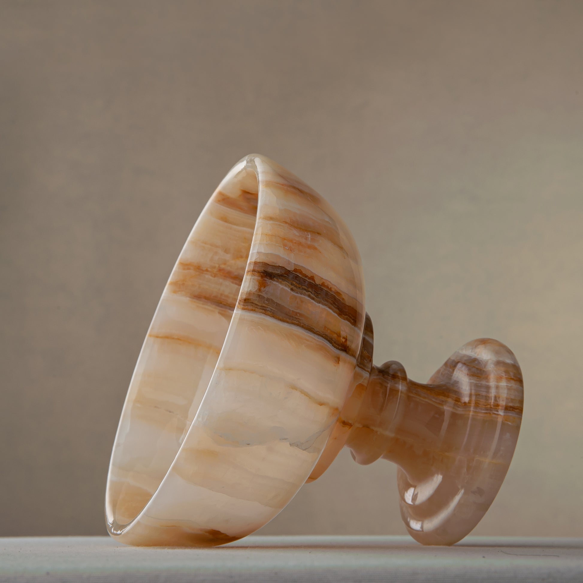 Unique natural onyx bowl with warm honey hues and elevated sculptural form for centerpiece styling
