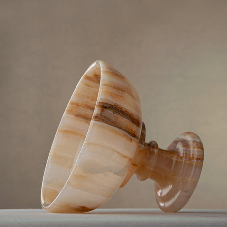 Unique natural onyx bowl with warm honey hues and elevated sculptural form for centerpiece styling
