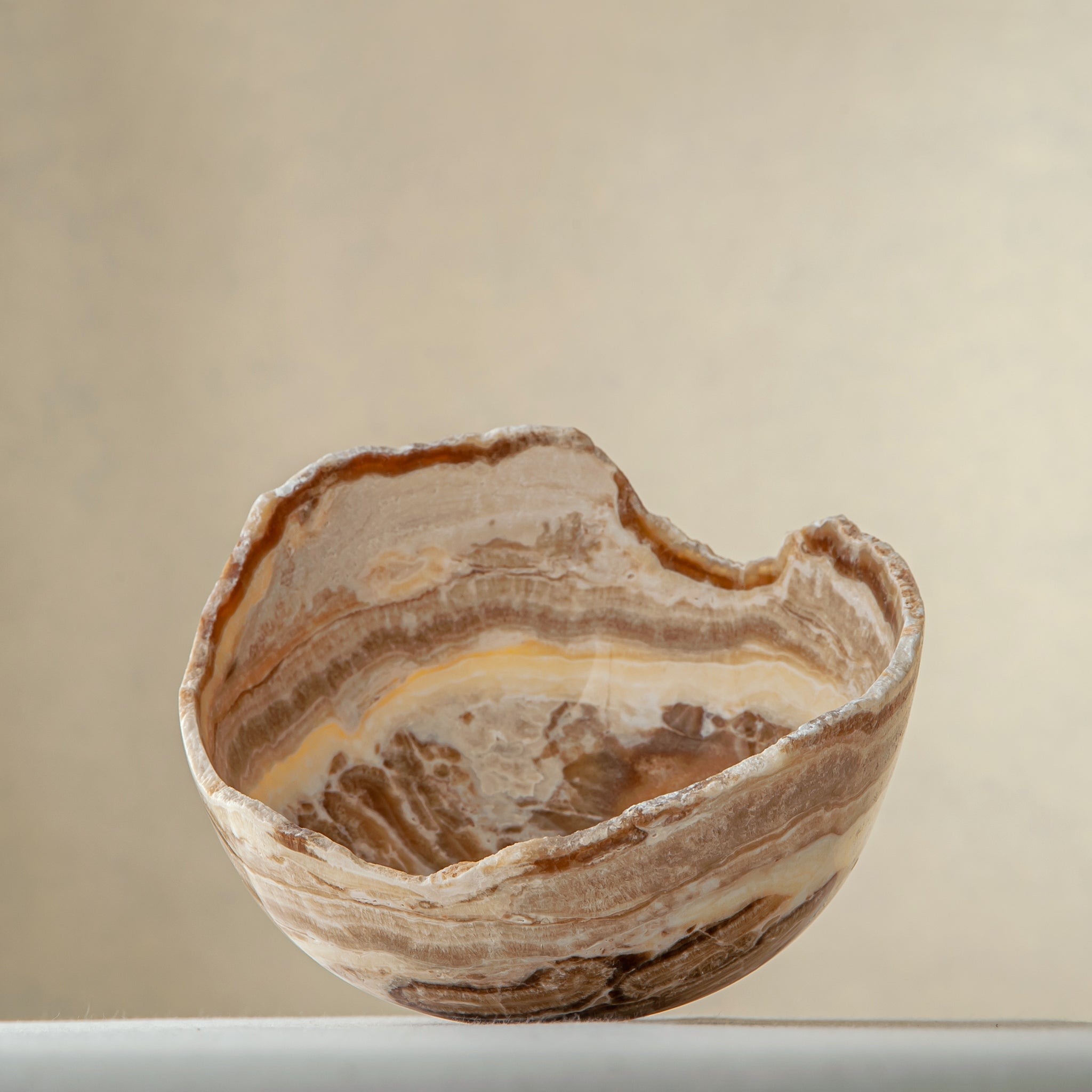 handcrafted stone bowl in onyx with textured edge and rich banding for coffee table styling