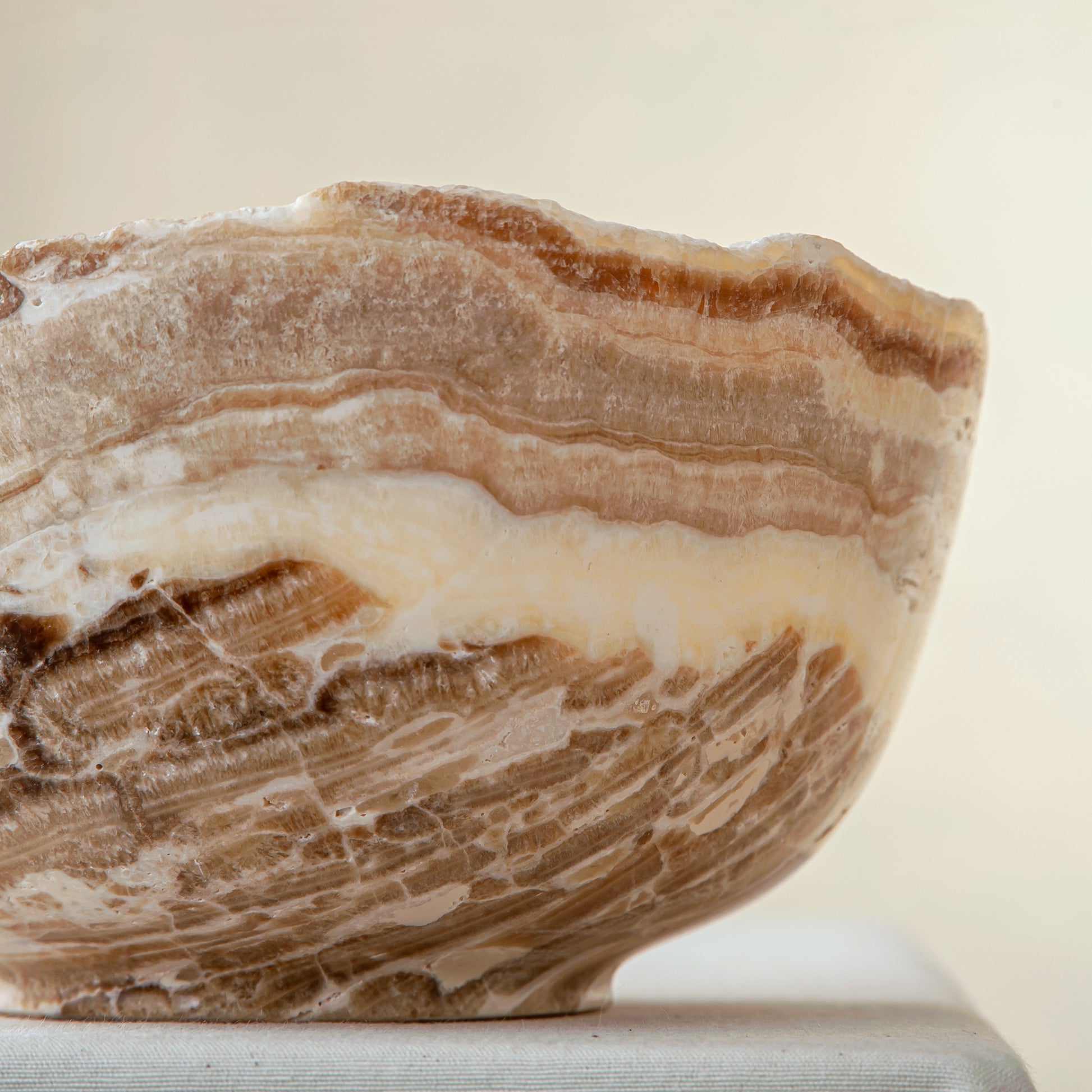 handcrafted stone bowl in onyx with textured edge and rich banding for coffee table styling