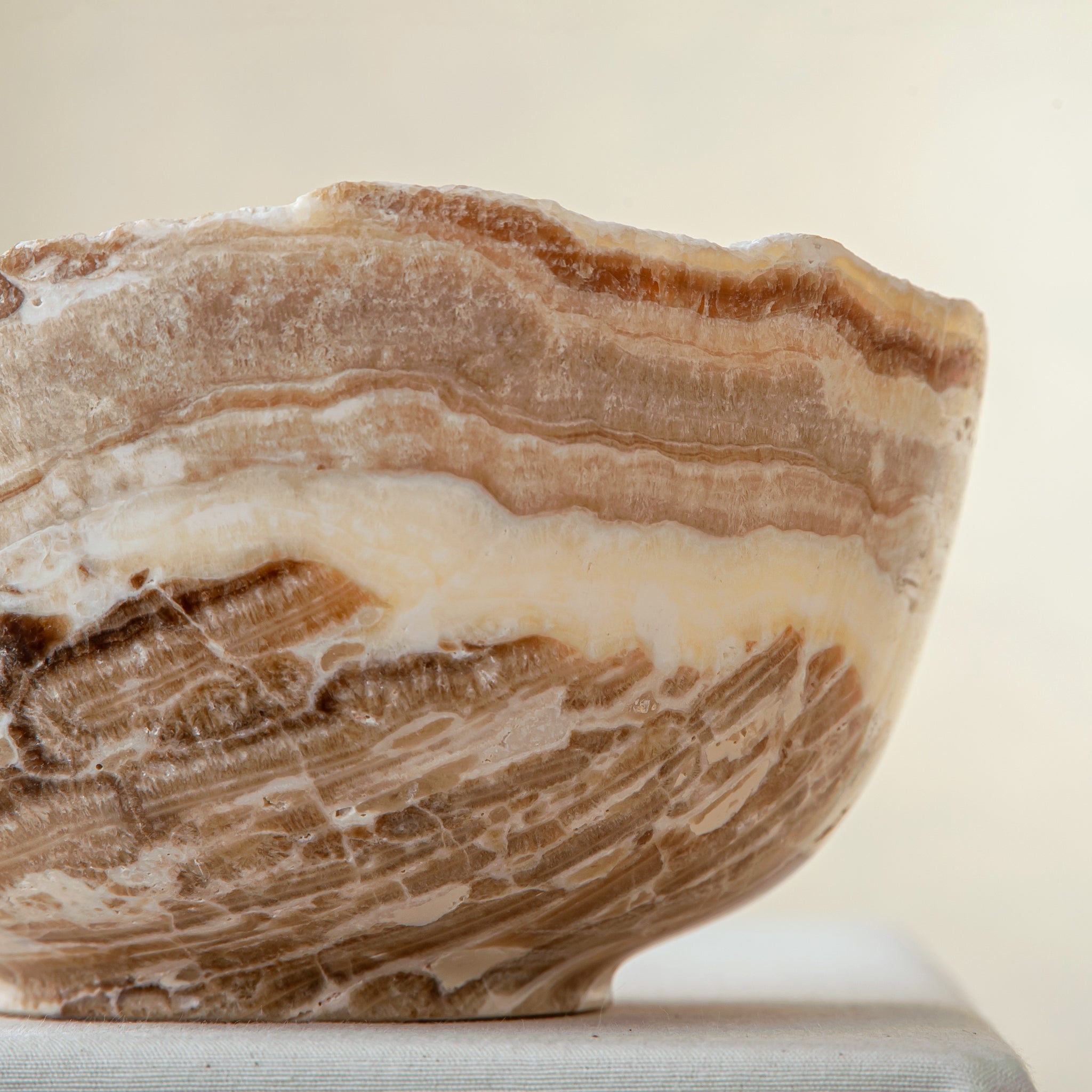 handcrafted stone bowl in onyx with textured edge and rich banding for coffee table styling